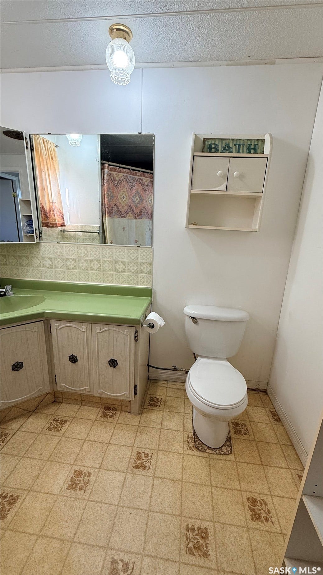Corner vanity with a green countertop and white cabinetry, accompanied by a standard toilet