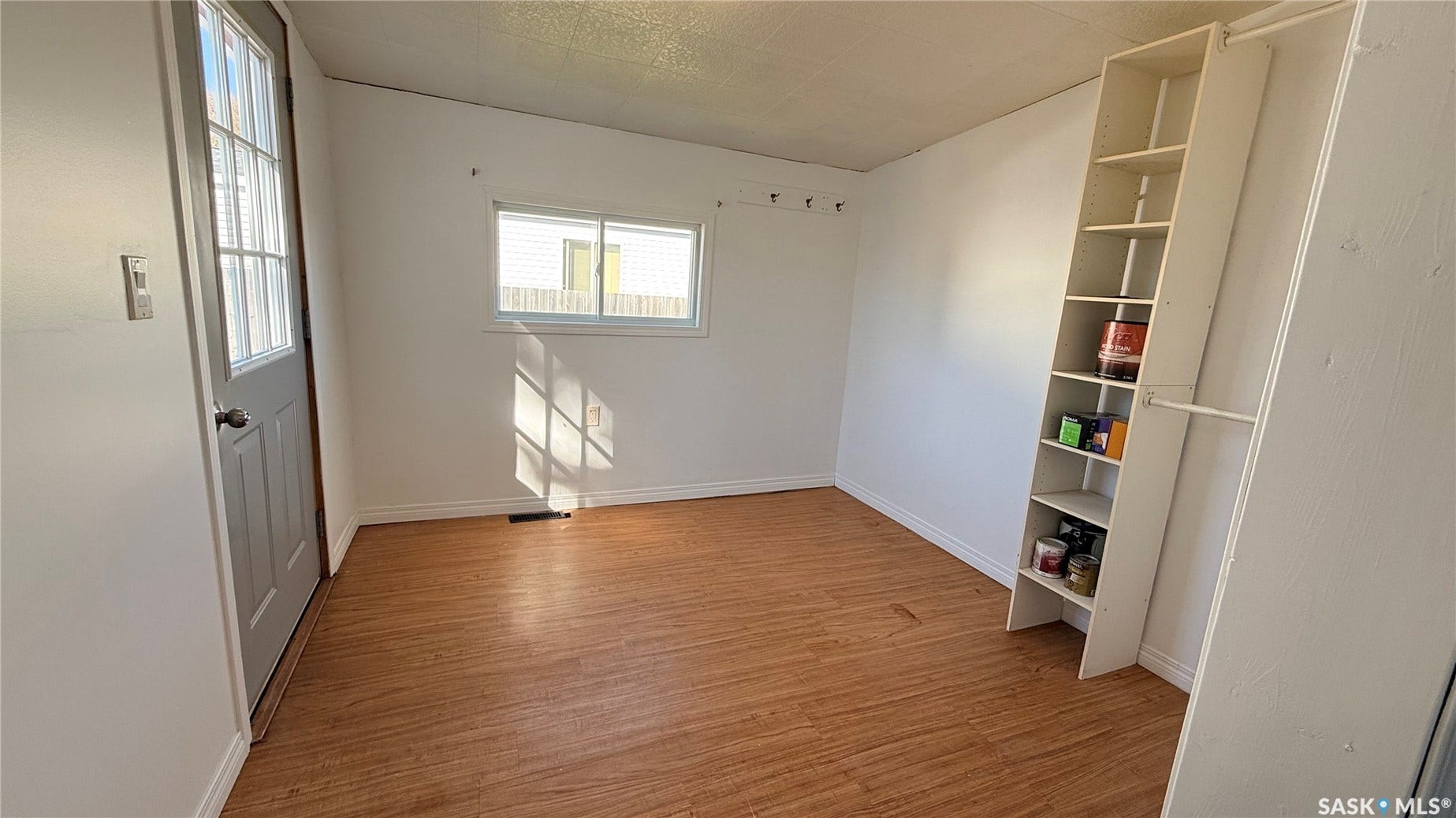 Wood-finish flooring, white walls, and a built-in shelving unit