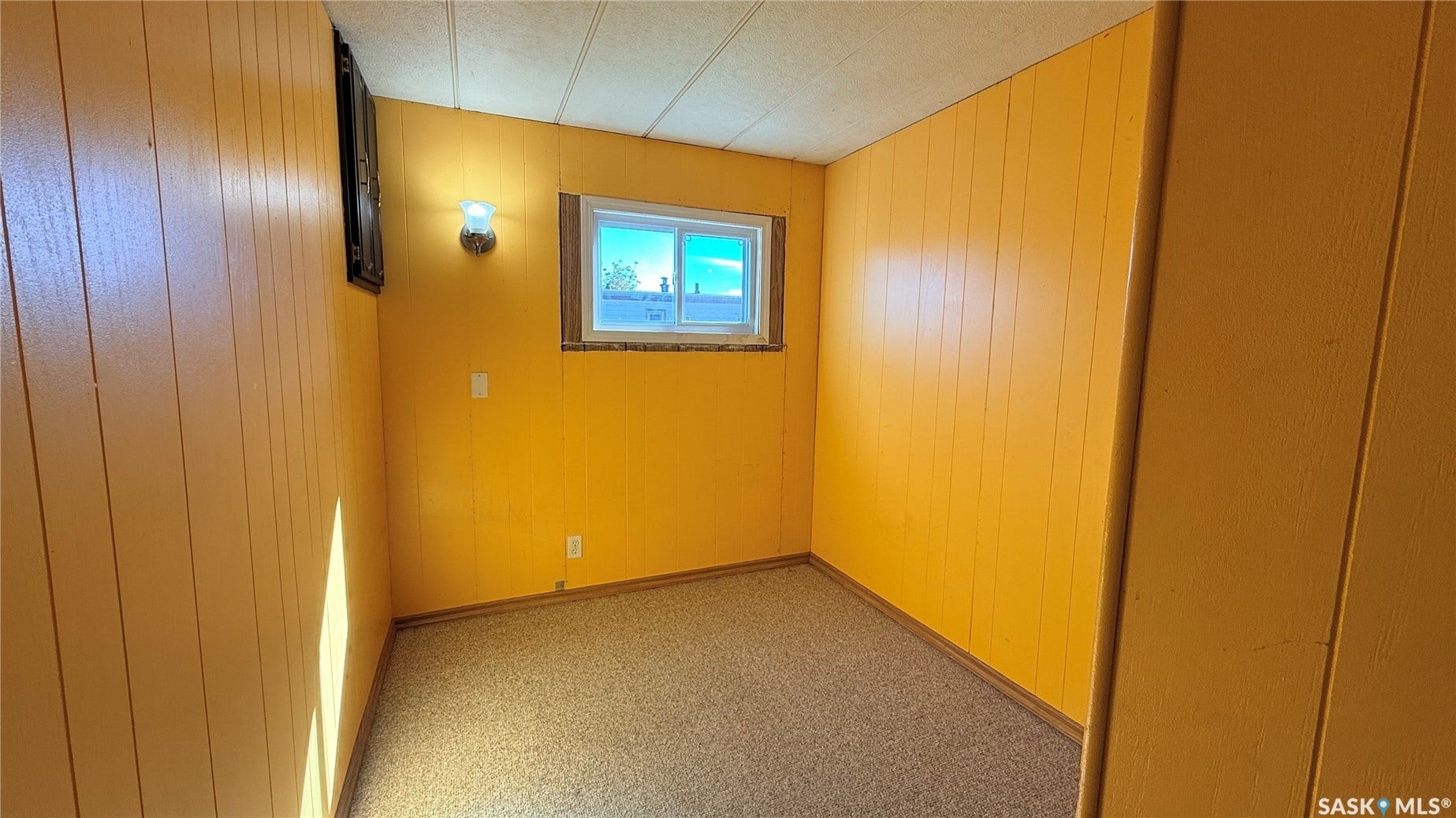 Windowed room featuring wall paneling and textured flooring