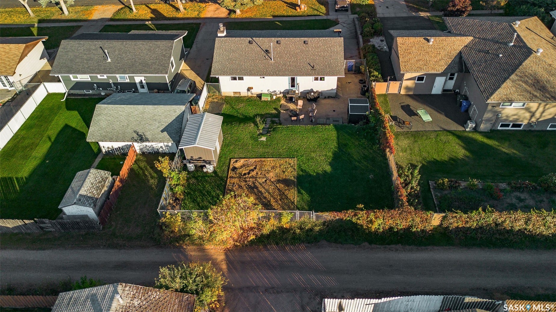 Expansive backyard with a manicured lawn, a concrete patio, and a storage shed