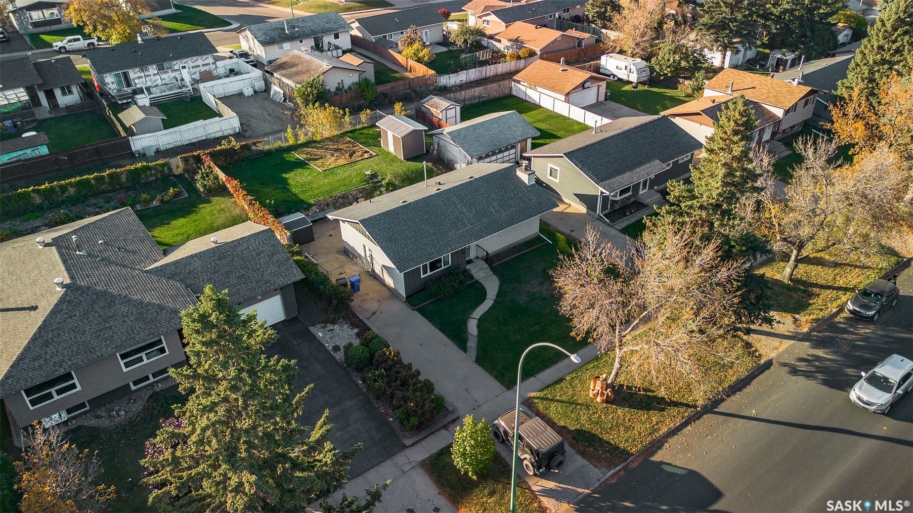 Spacious lot featuring a paved driveway, attached garage, and mature trees