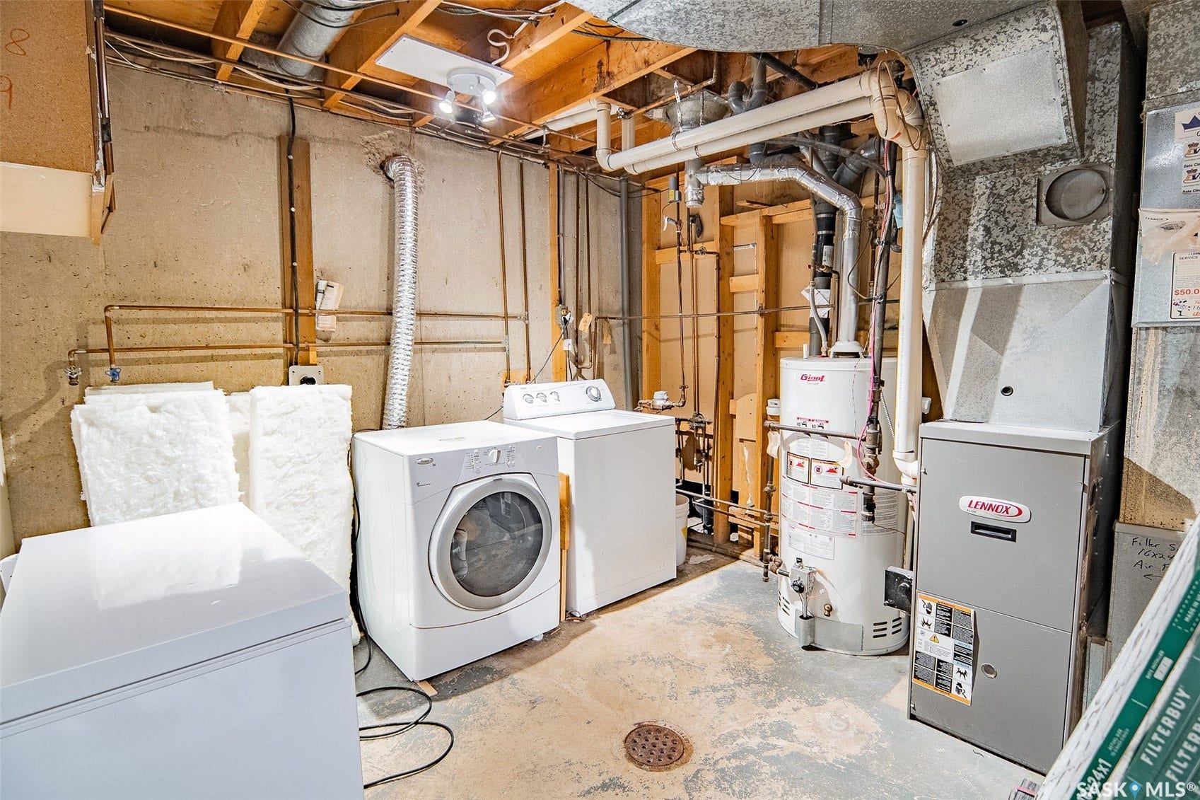Basement utility area featuring a front-load washer, a top-load dryer, a water heater, and a furnace unit