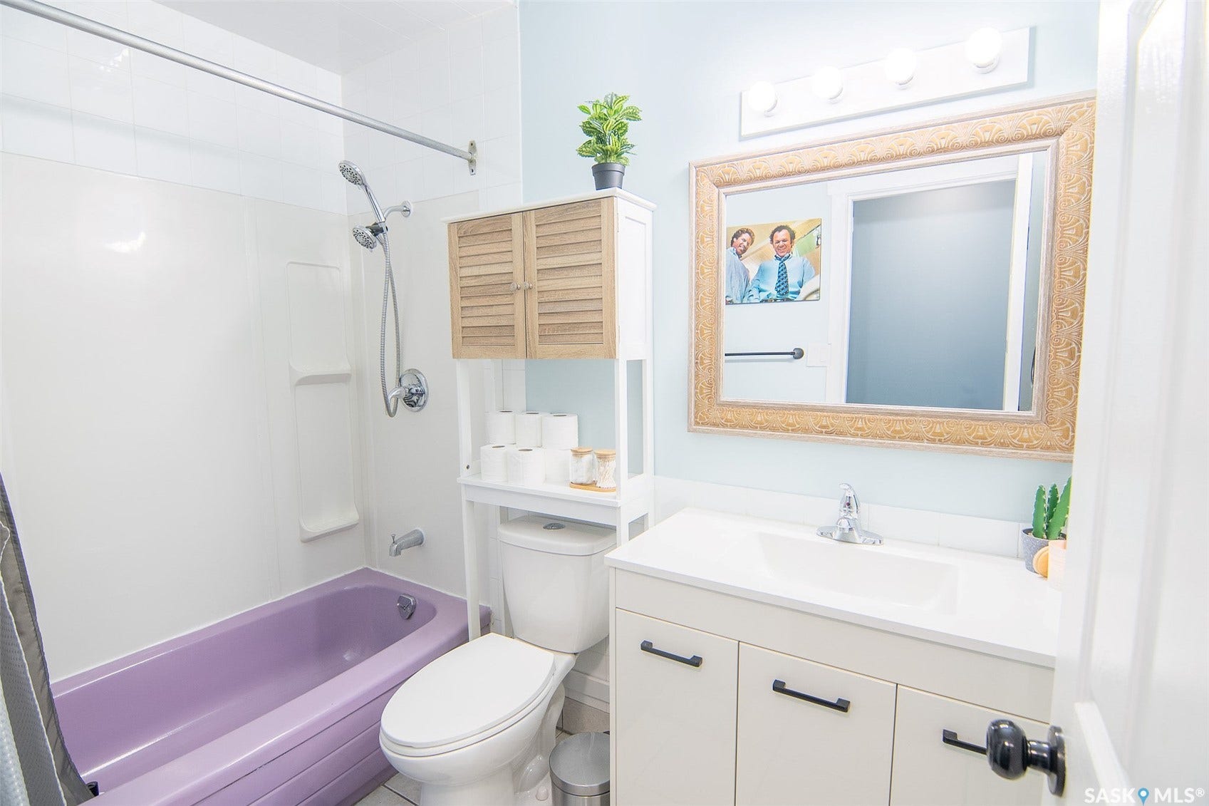 Bathroom featuring a white vanity with a single basin sink, an ornate framed mirror, and a built-in shower/tub combination