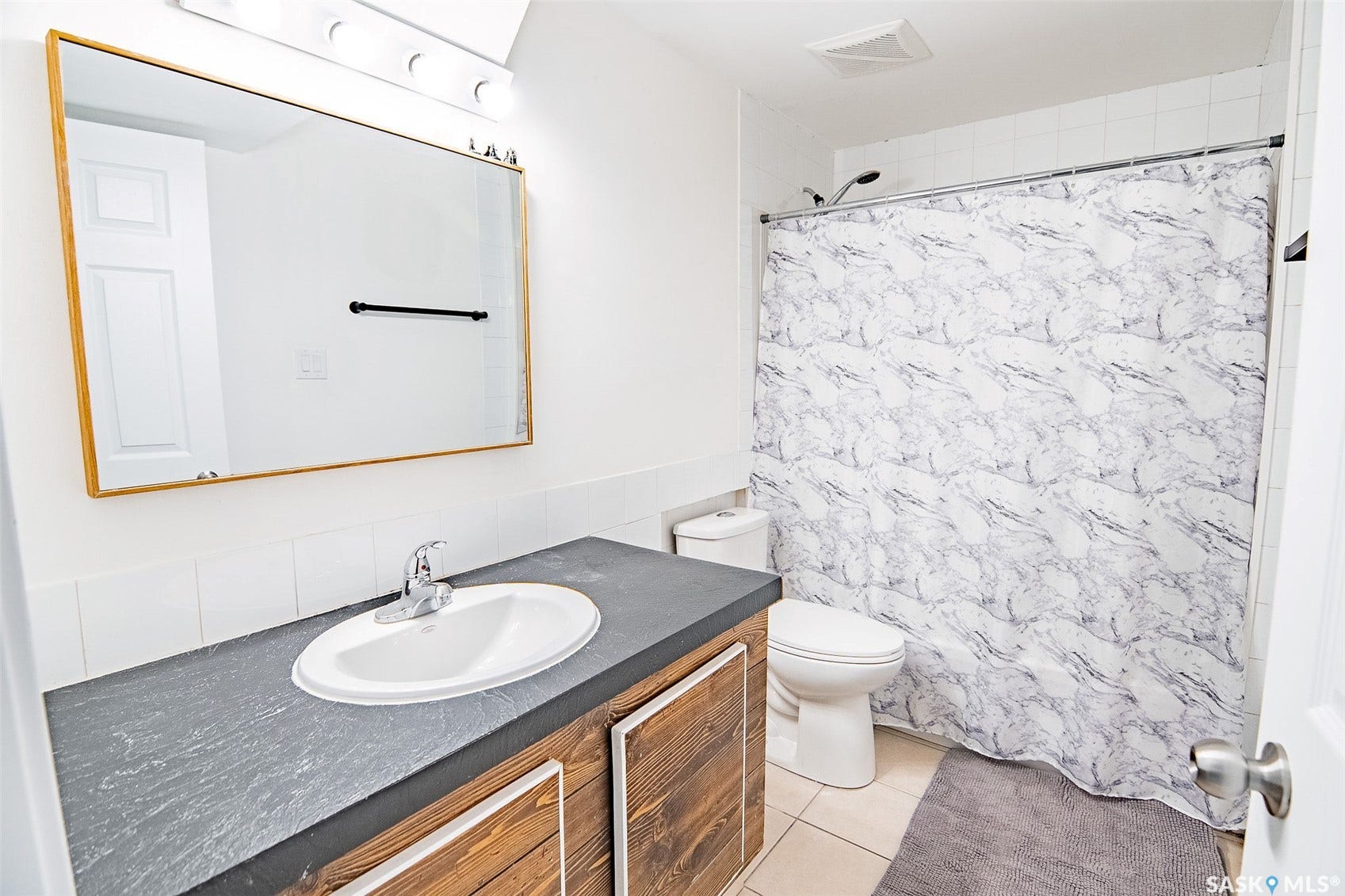 Vanity with an integrated oval sink, wood-finish cabinetry, and a dark-toned countertop