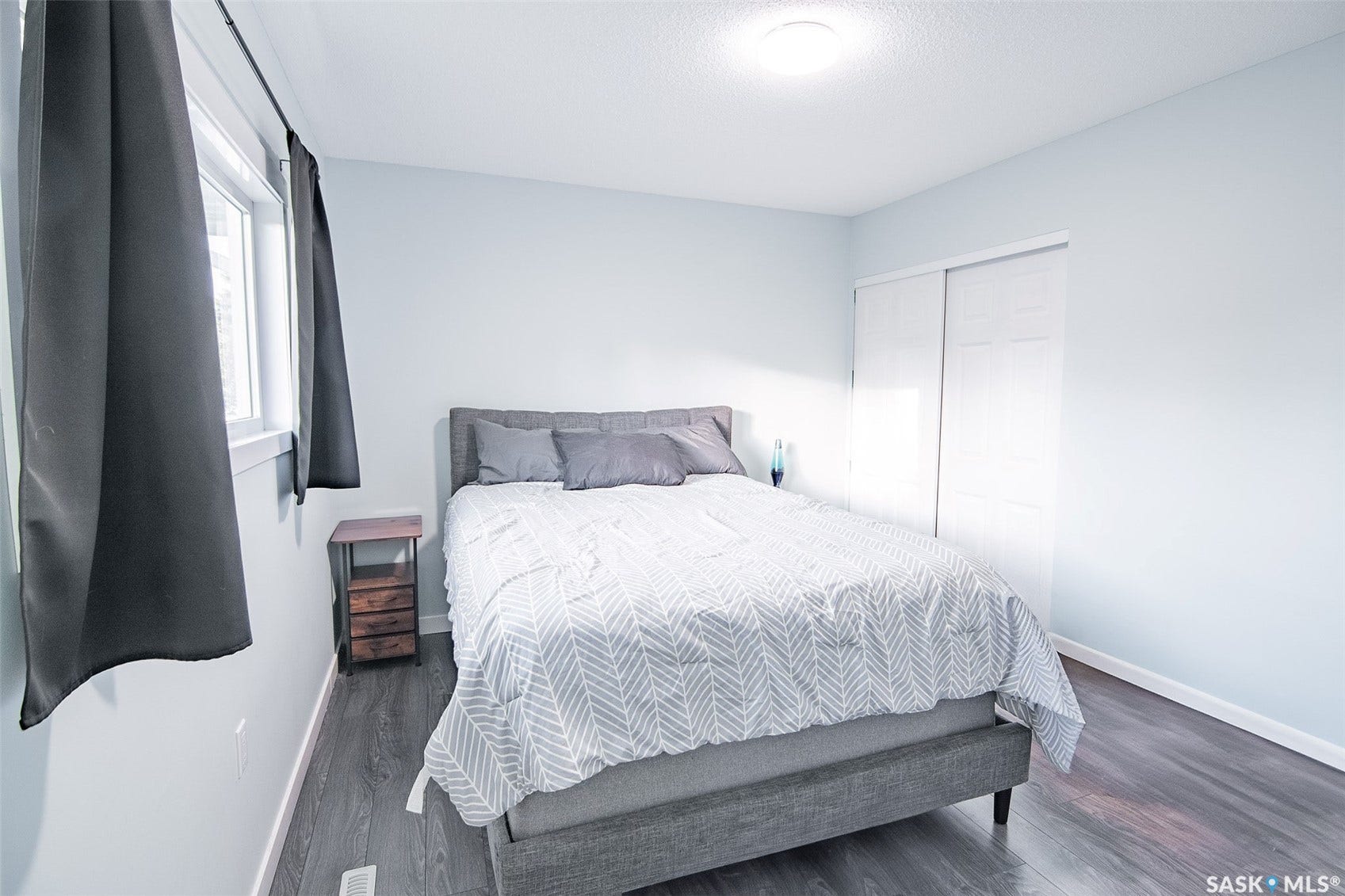 Wood-finish flooring, white walls, and a window with trim