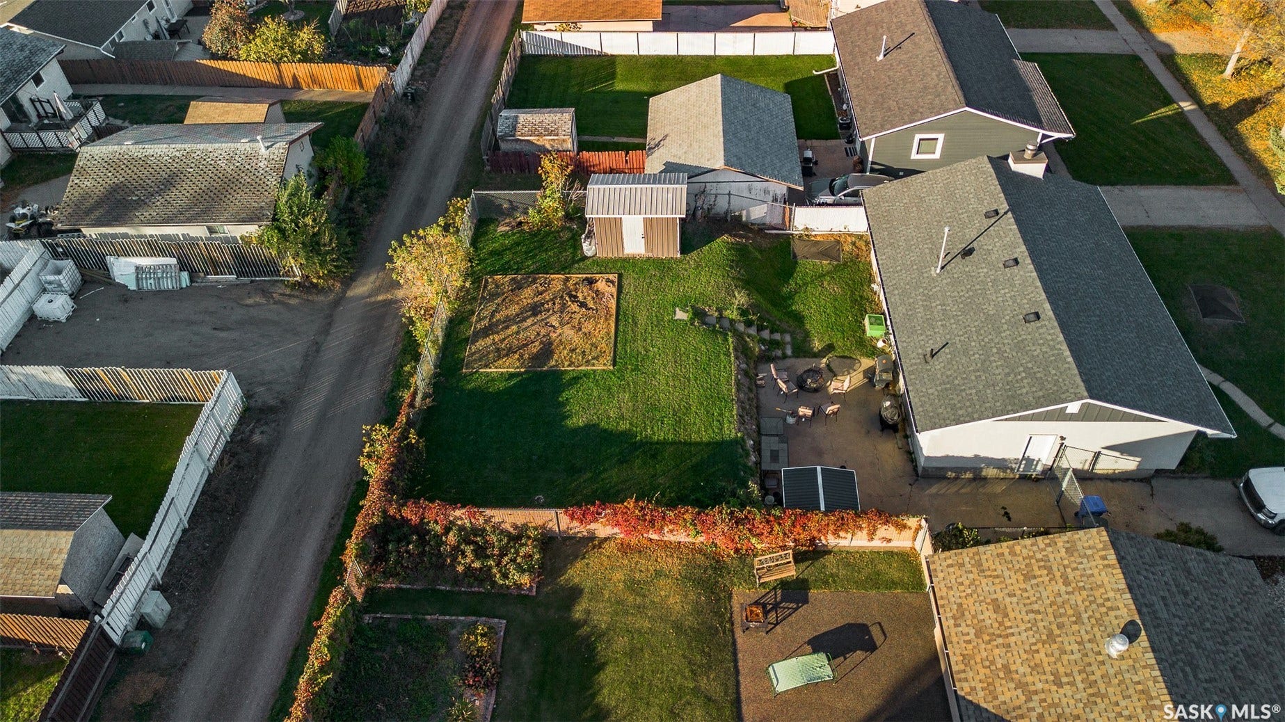 Expansive lot featuring a detached storage shed, lush green lawn, and a designated garden area