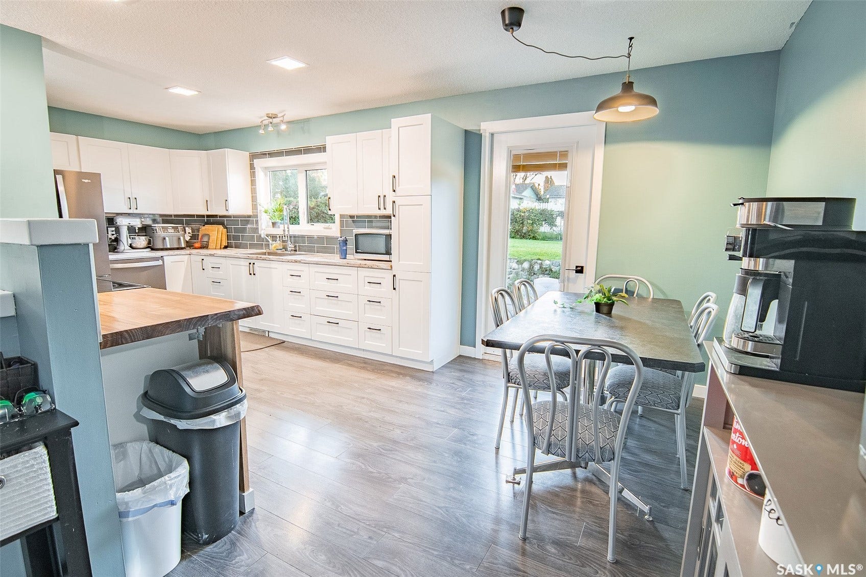 Kitchen featuring white shaker cabinetry, stainless steel appliances, wood-finish flooring, and a tile backsplash