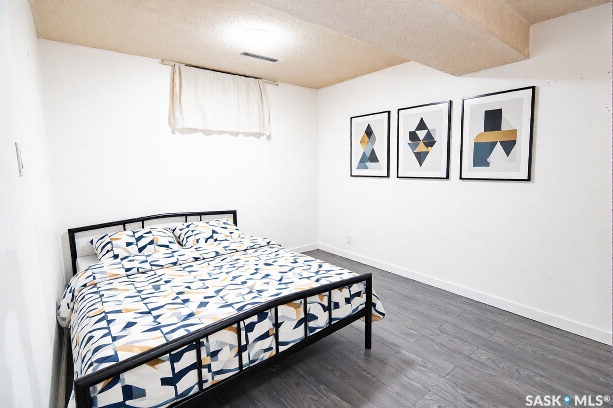 White walls with white trim, wood-finish flooring, and a window with a sheer curtain