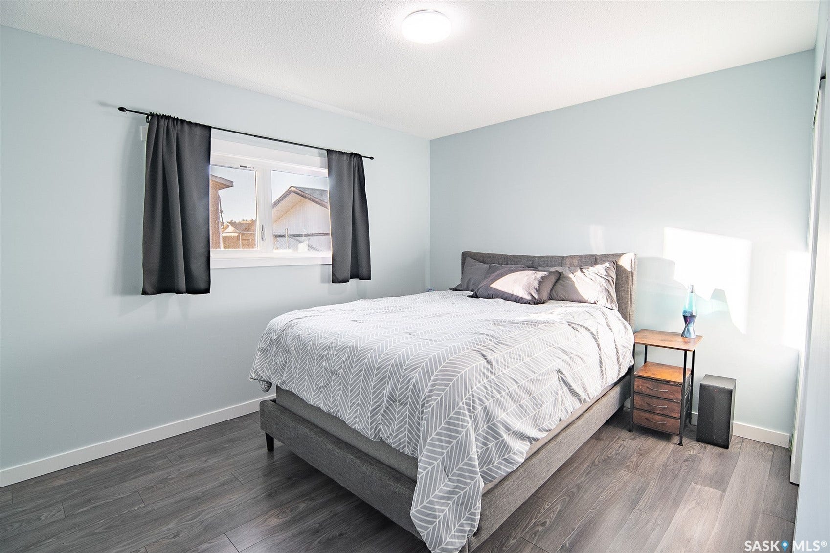 Wood-finish flooring, overhead lighting, and a window with white trim