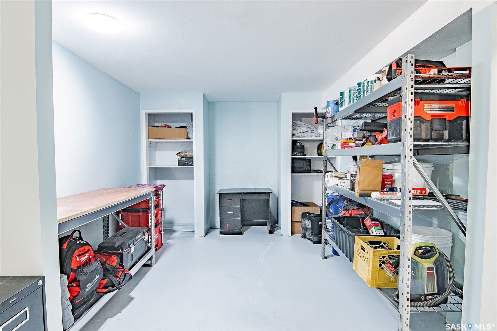 Dedicated storage area featuring built-in shelving, a workbench, and light-toned walls