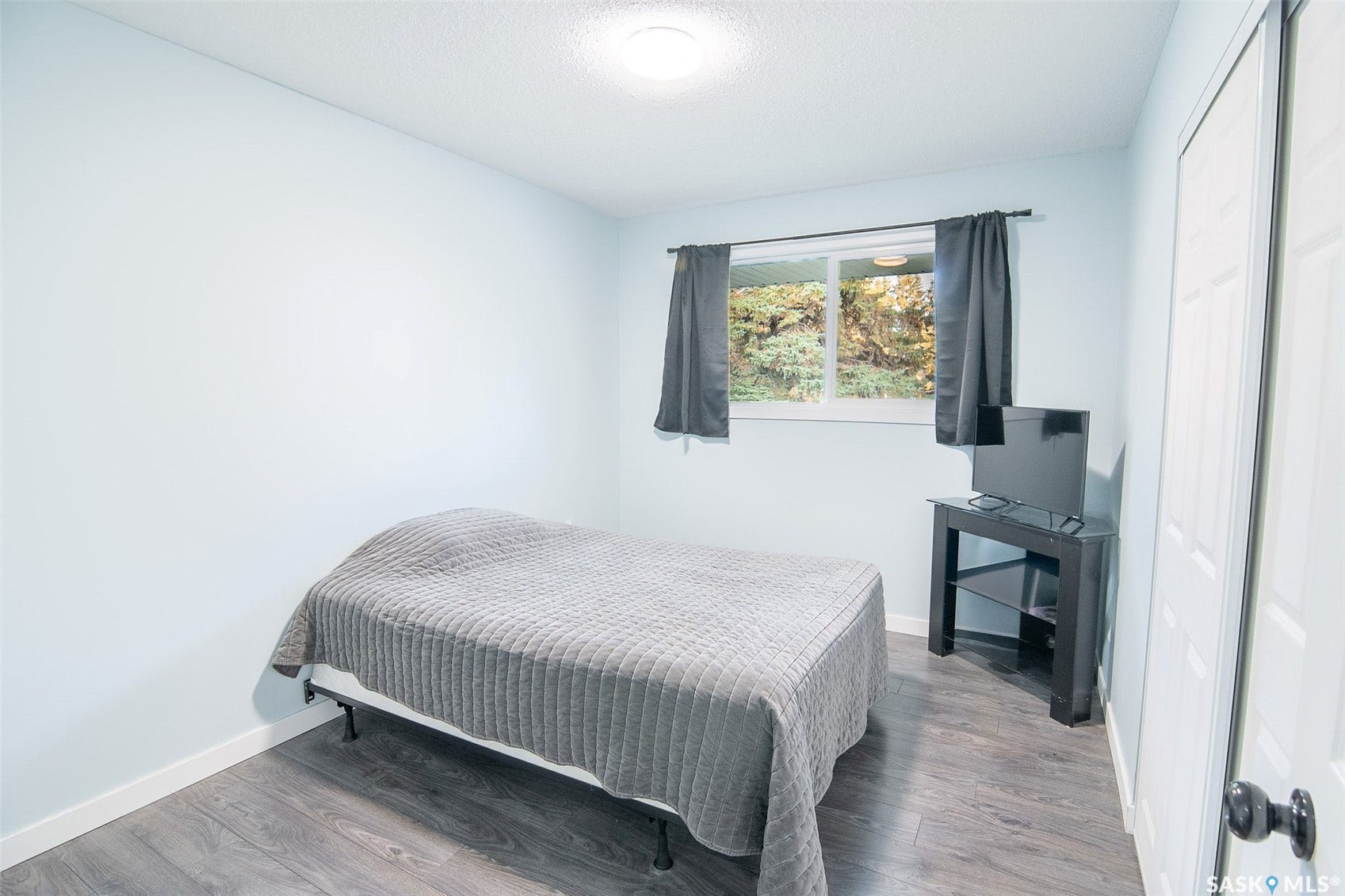 Light blue painted walls, wood-finish flooring, and a ceiling-mounted light fixture