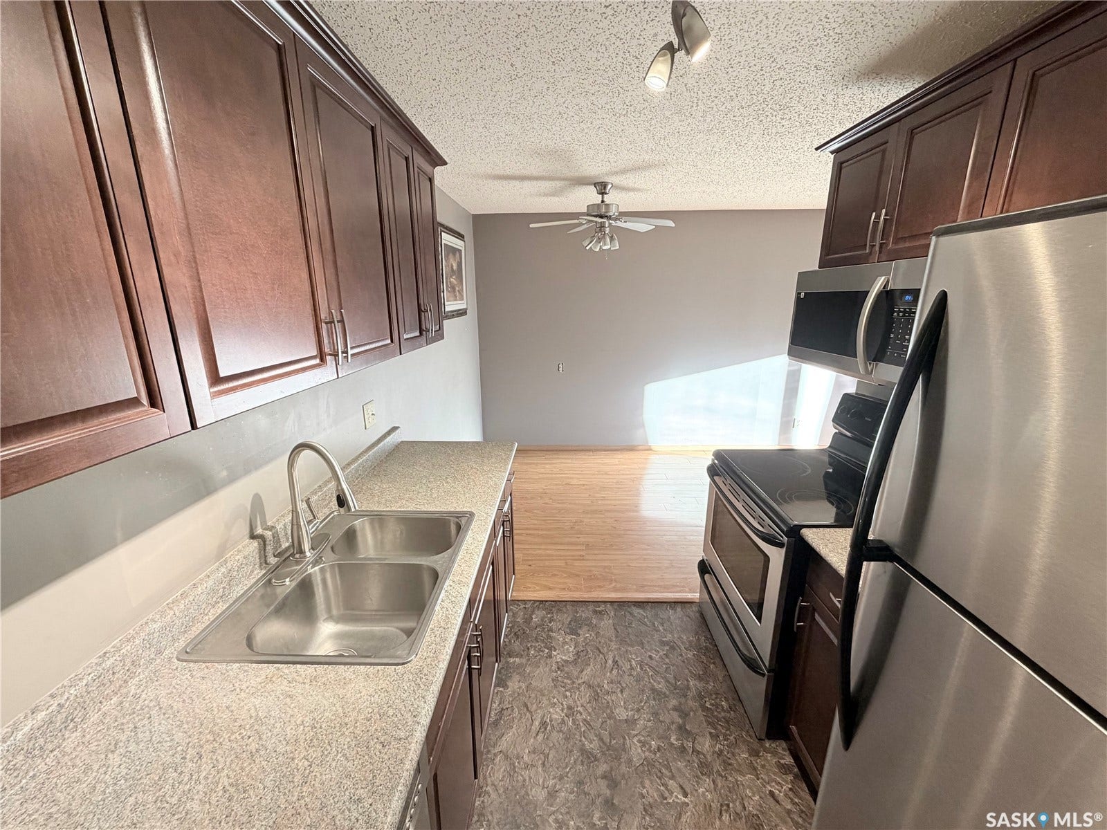 Full kitchen with stainless steel appliances, wood-finish cabinetry, and a dual basin sink
