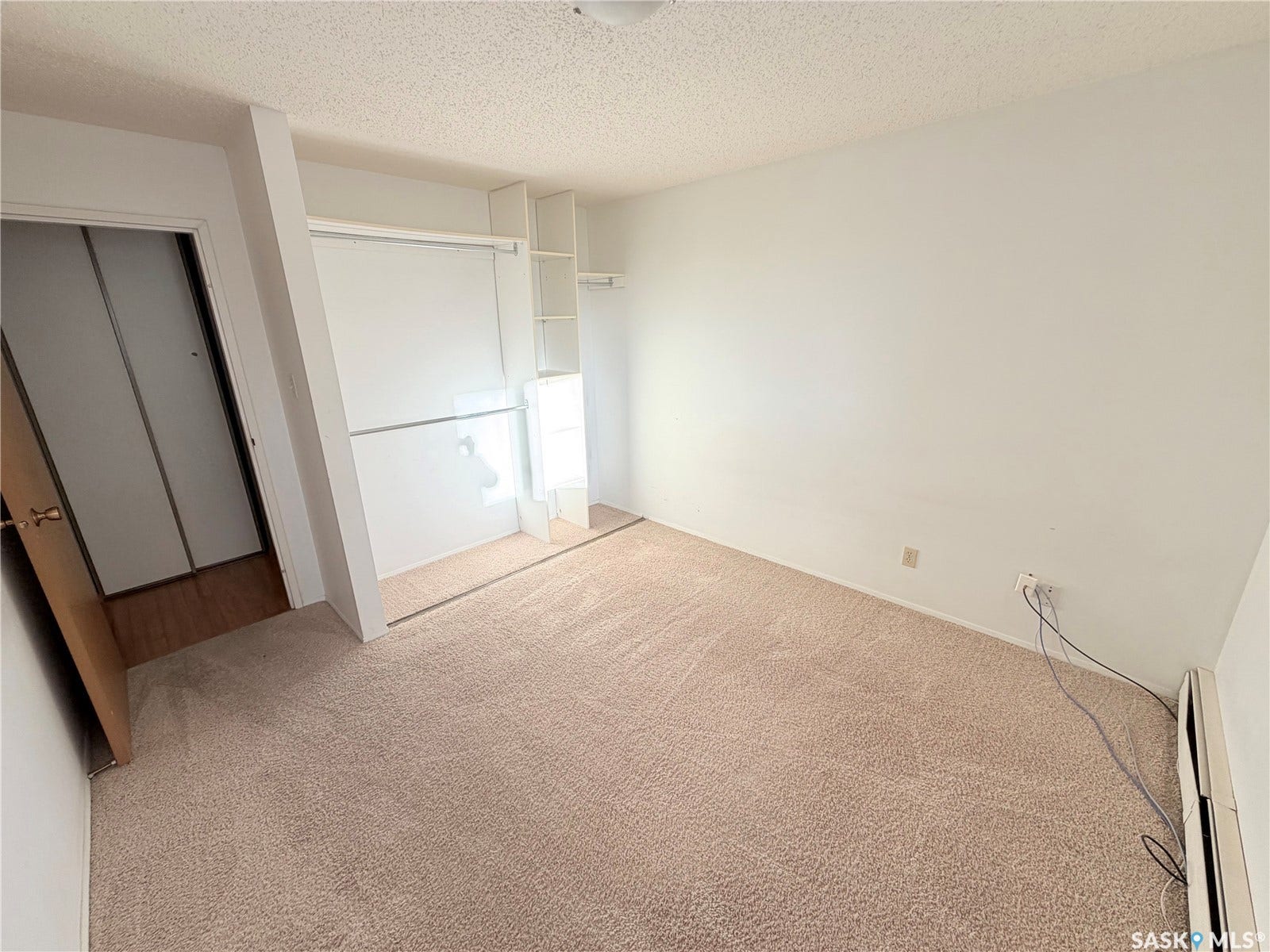Neutral tone wall paint, textured ceiling, built-in shelving, carpet flooring, wood-finish door