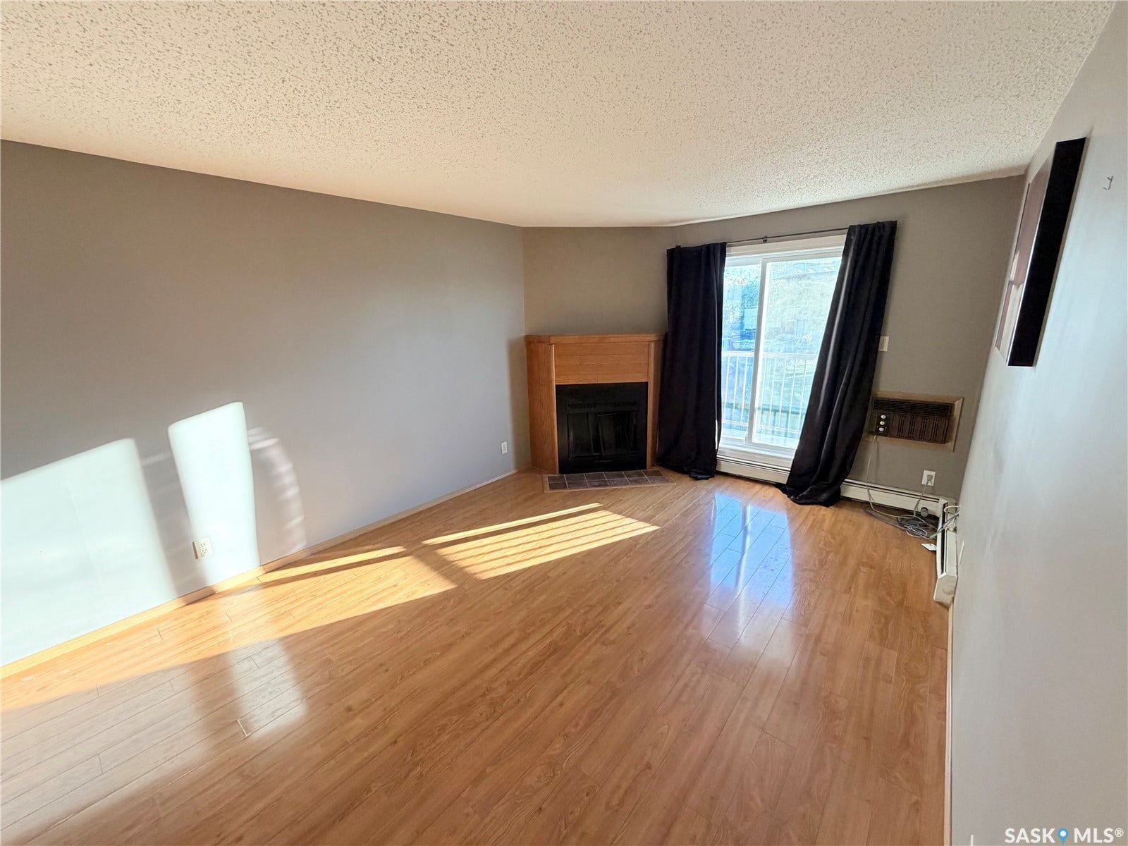 Wood-finish flooring throughout, featuring a corner fireplace with a wood surround and tiled hearth