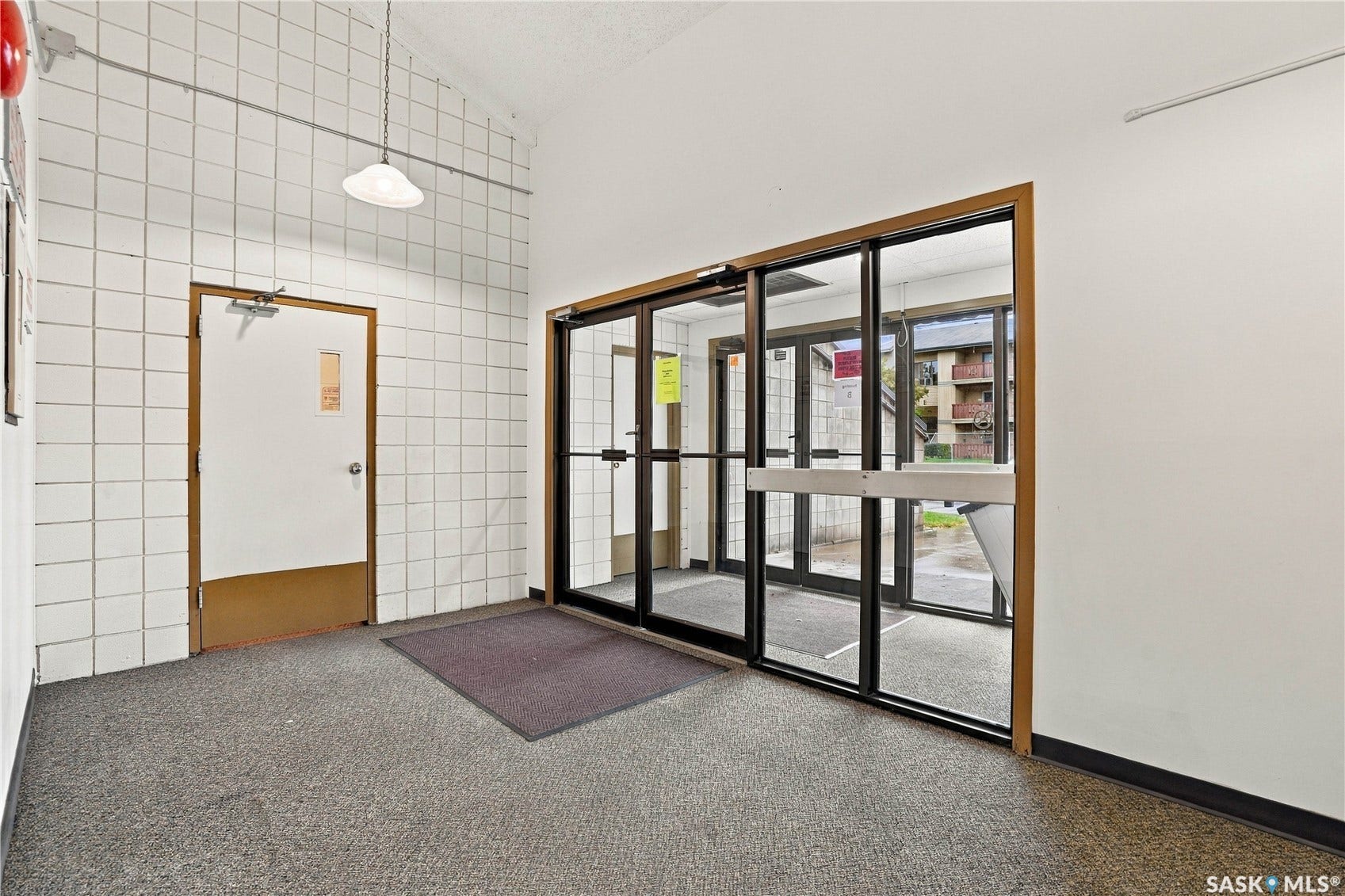 Tiled wall accents, dual glass doors, and suspended lighting fixture