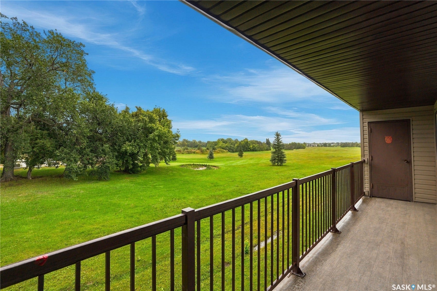 Private outdoor balcony with metal railing, offering expansive green landscaping