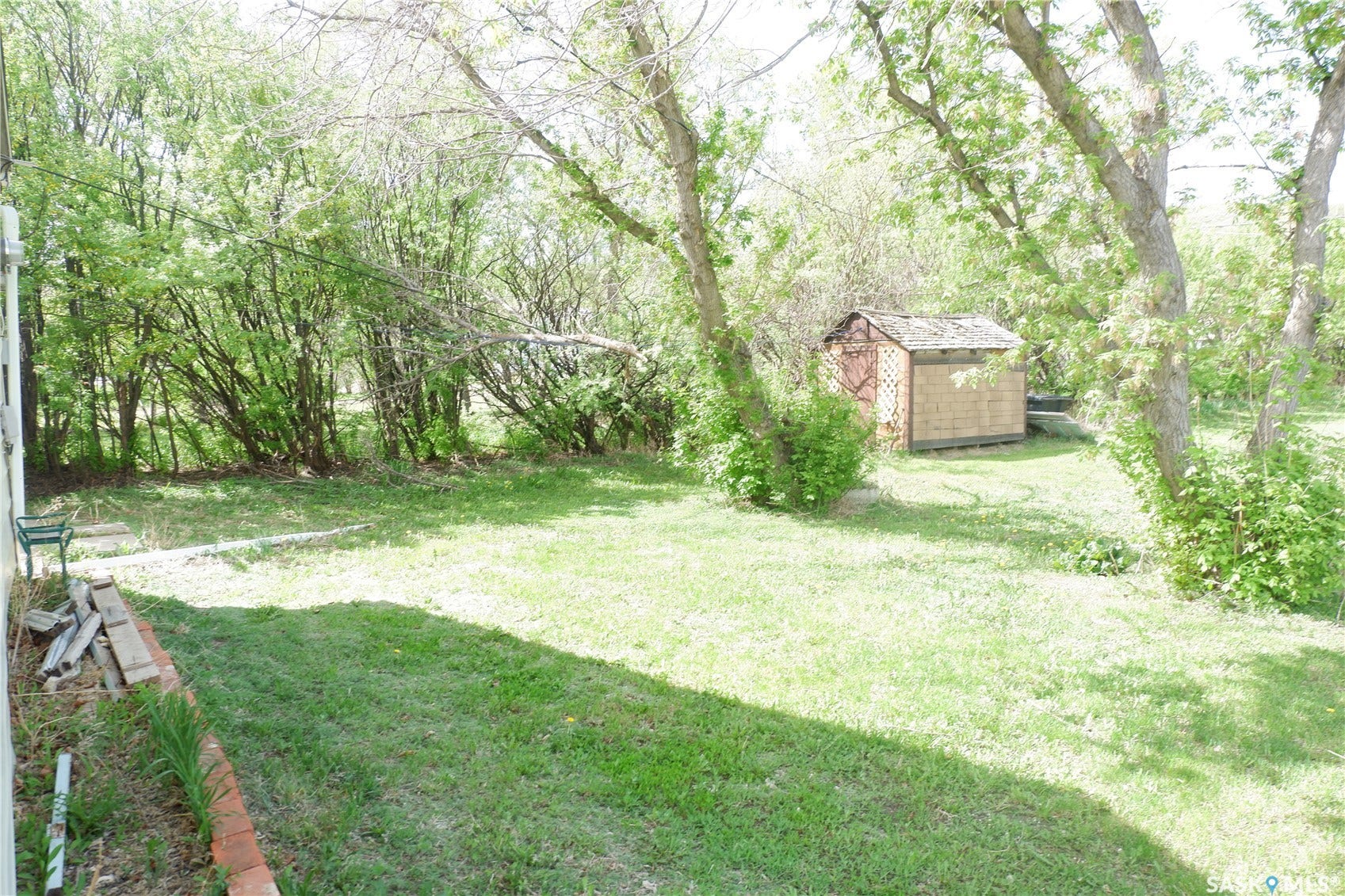 View of grassy yard featuring a storage shed and an outbuilding