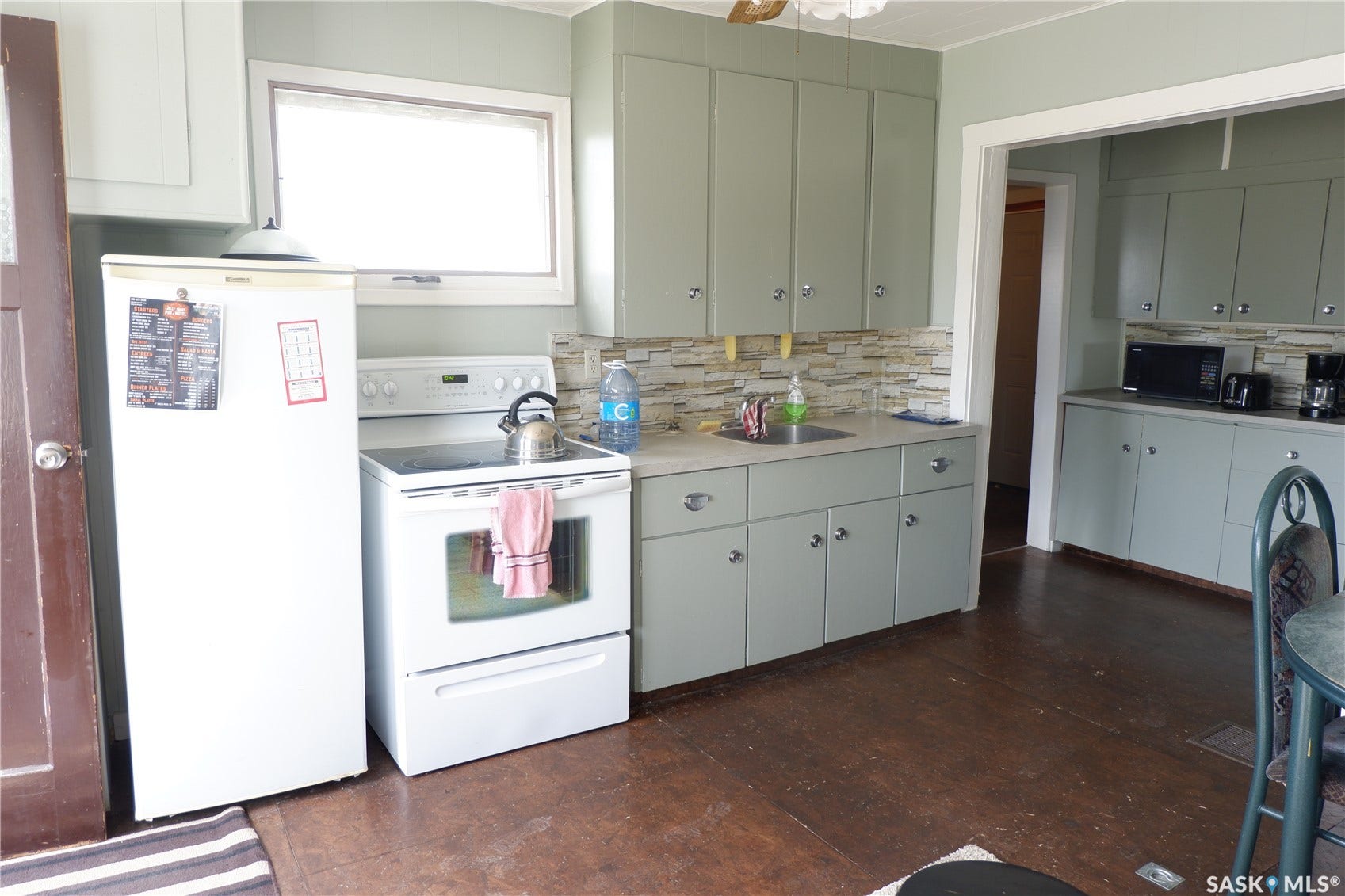 Kitchen with white electric stove, refrigerator, decorative backsplash, black microwave, and a sink