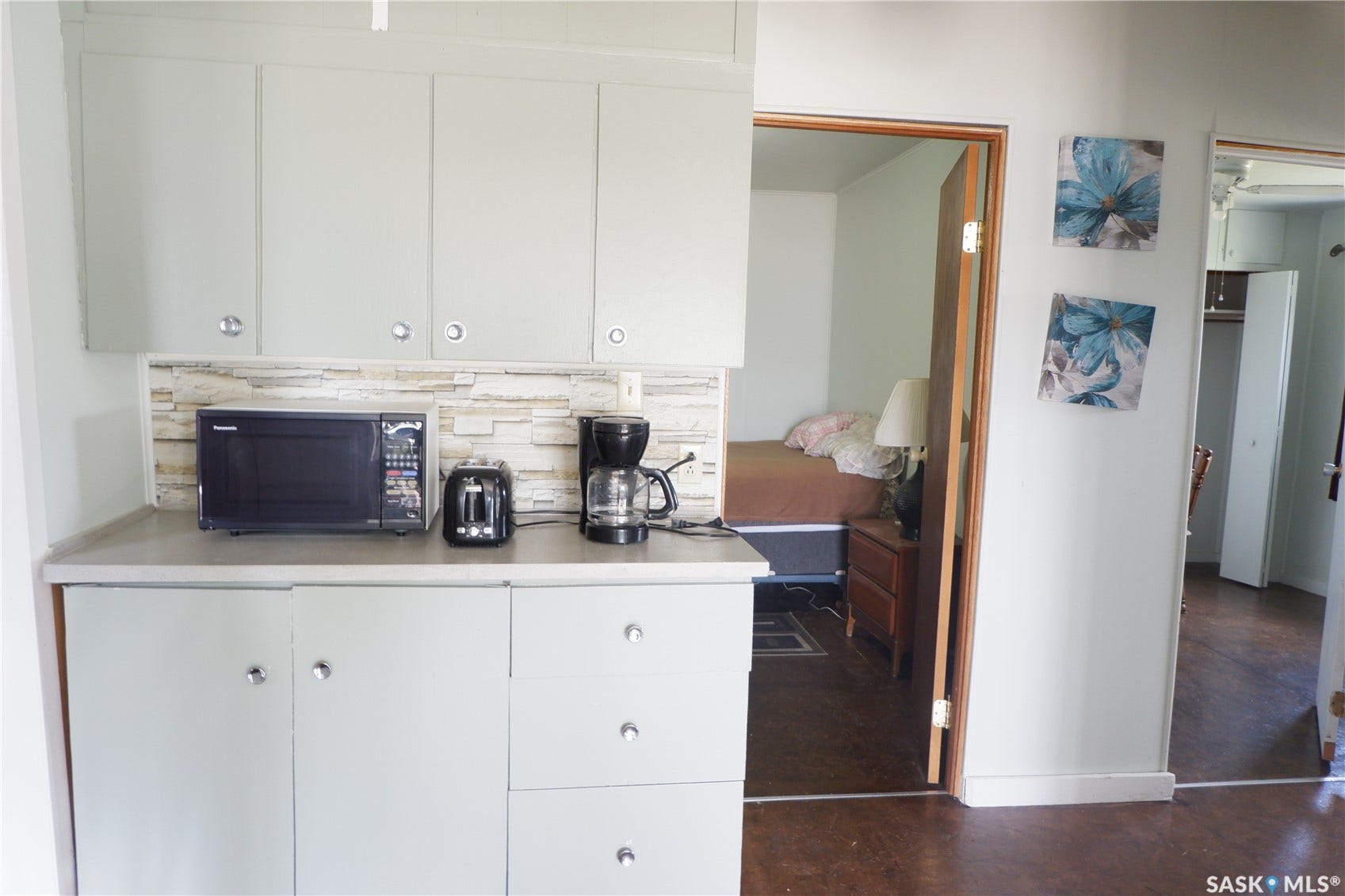 Kitchen featuring black microwave, light countertops, white cabinets, and finished concrete flooring
