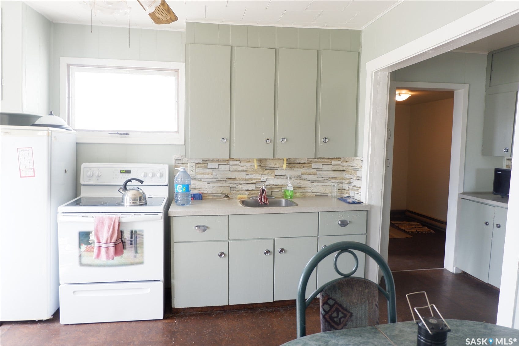 Kitchen featuring white appliances, a sink, tasteful backsplash, light countertops, and a ceiling fan