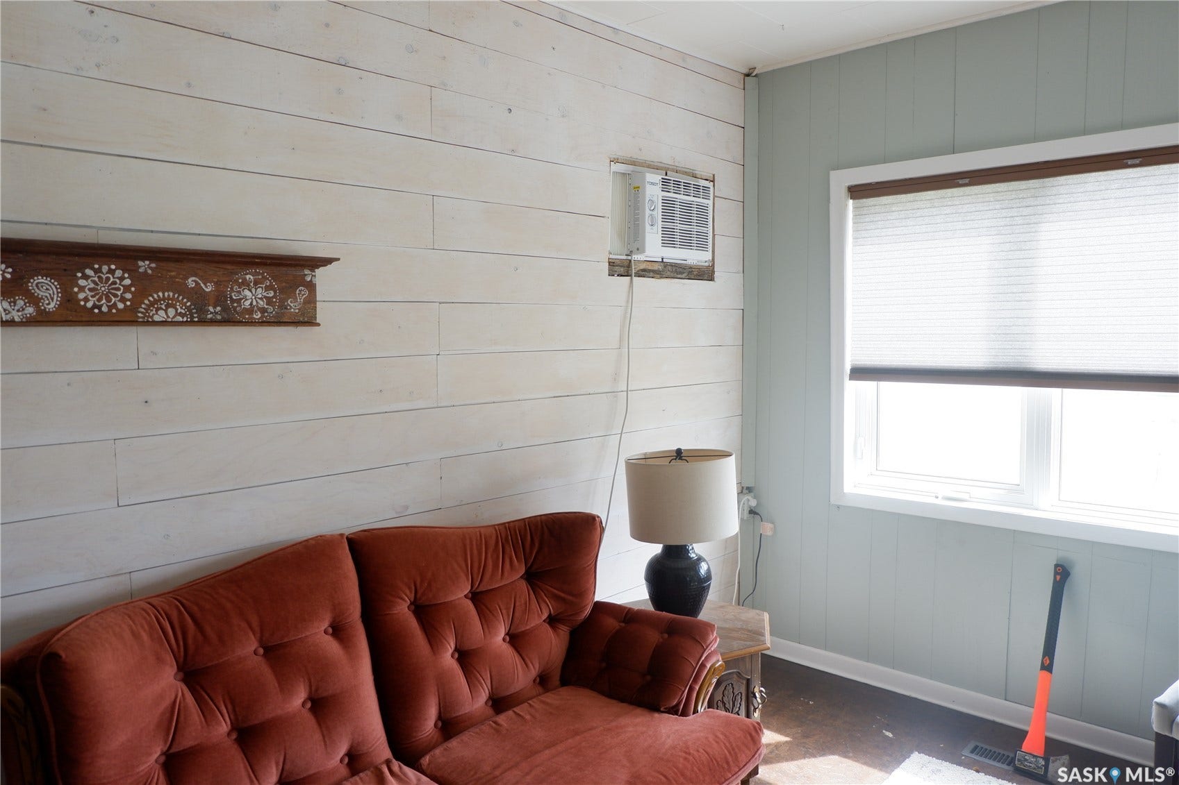 Living room featuring an AC wall unit, baseboards, and wood walls
