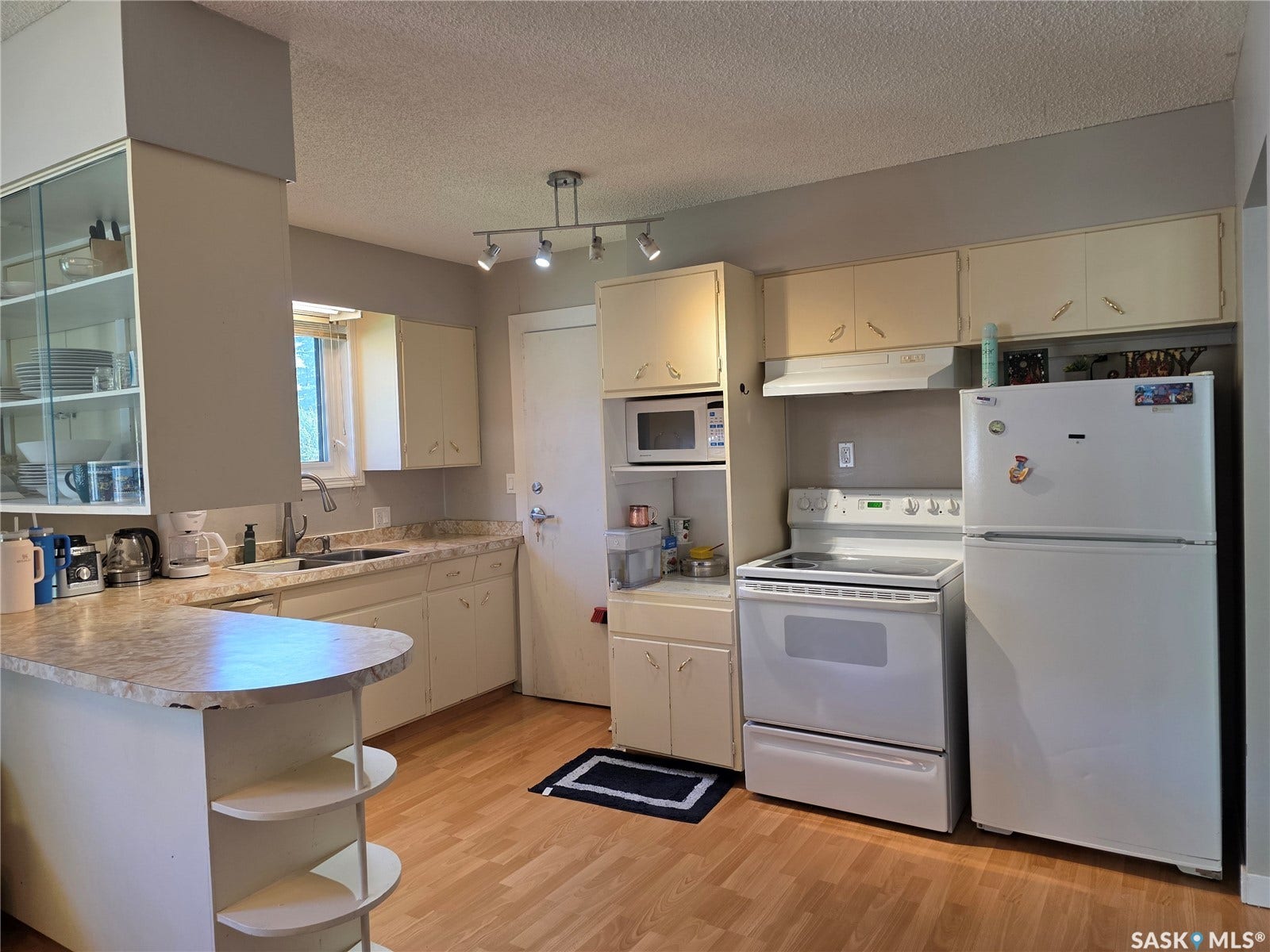 Kitchen featuring wood-finish flooring, white cabinetry, a double basin sink, and white appliances