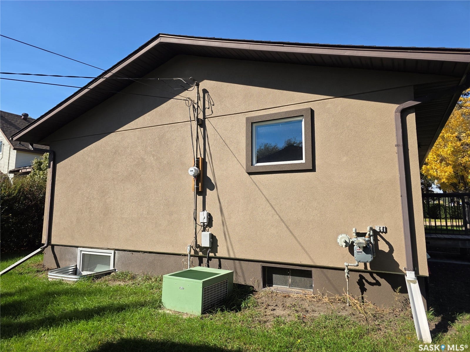 Stucco exterior with contrasting trim, rectangular window with white frame, and a basement egress window