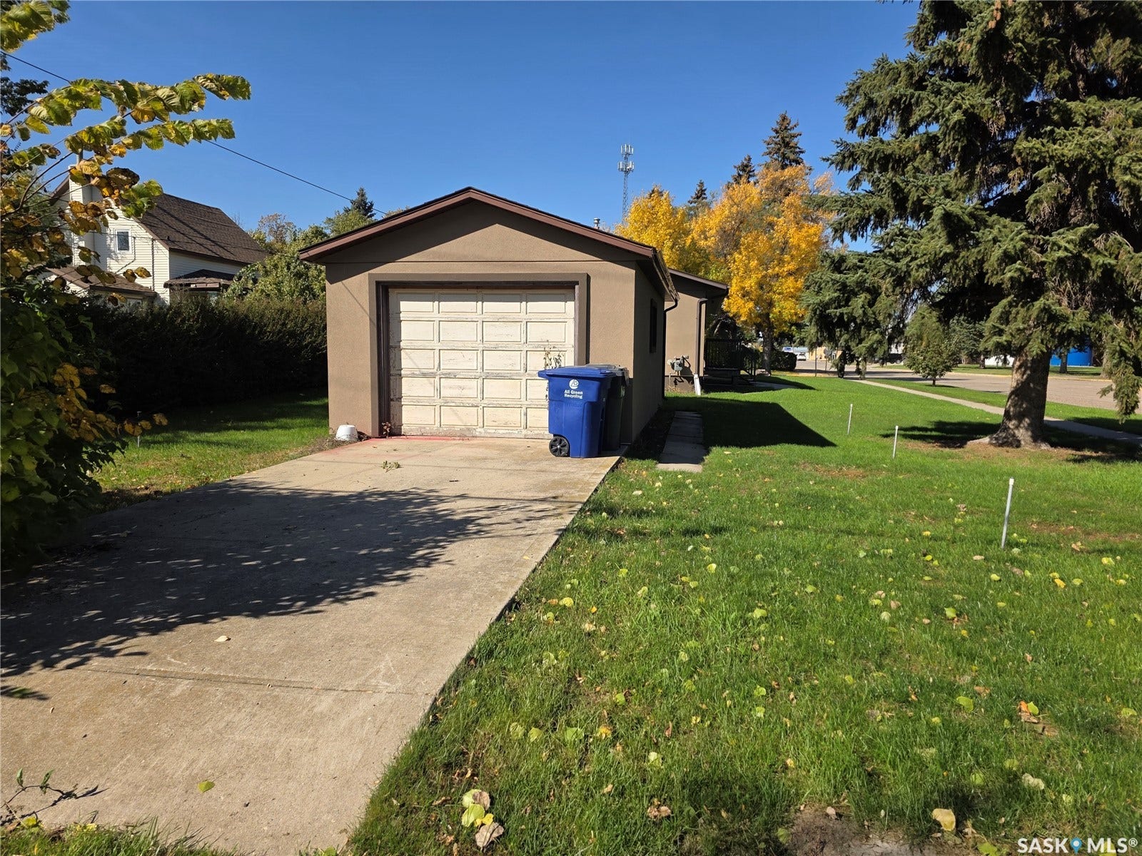 Detached garage with stucco exterior, concrete driveway, and a spacious green lawn