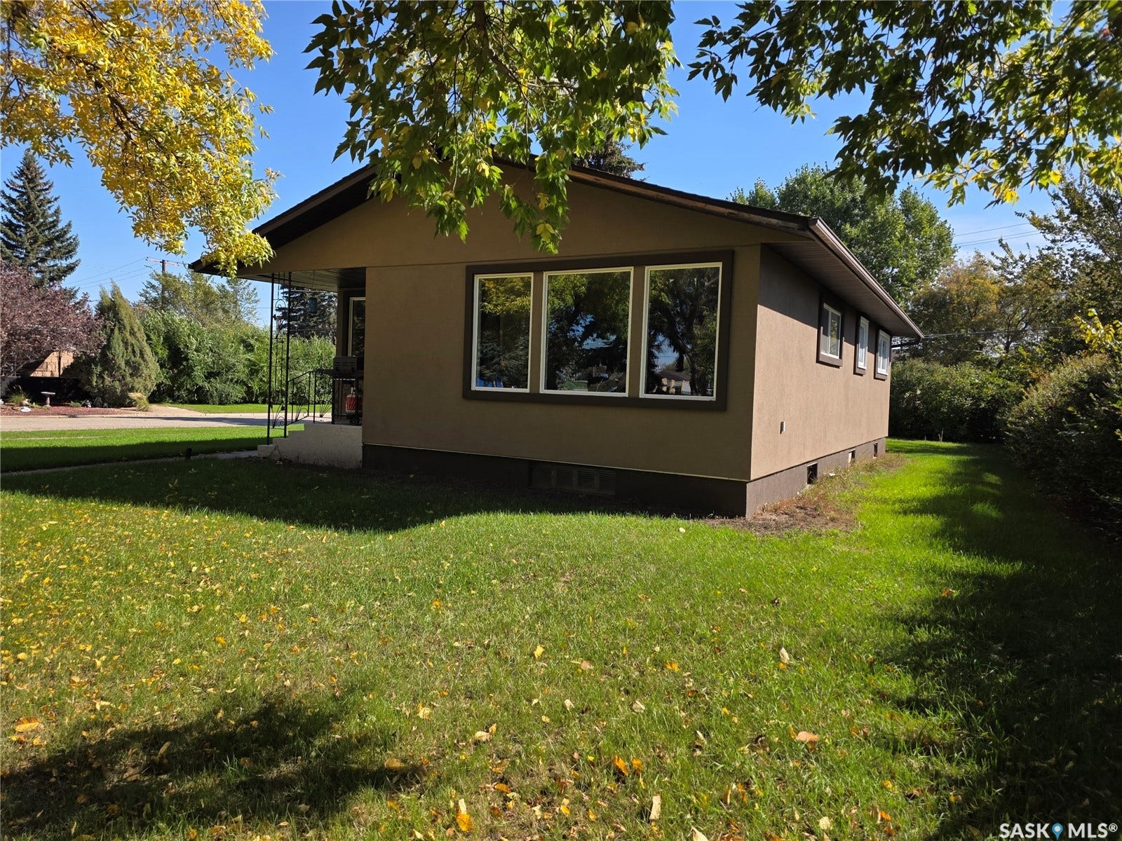 Stucco exterior with multiple windows, pitched roofline, and front entry with railing