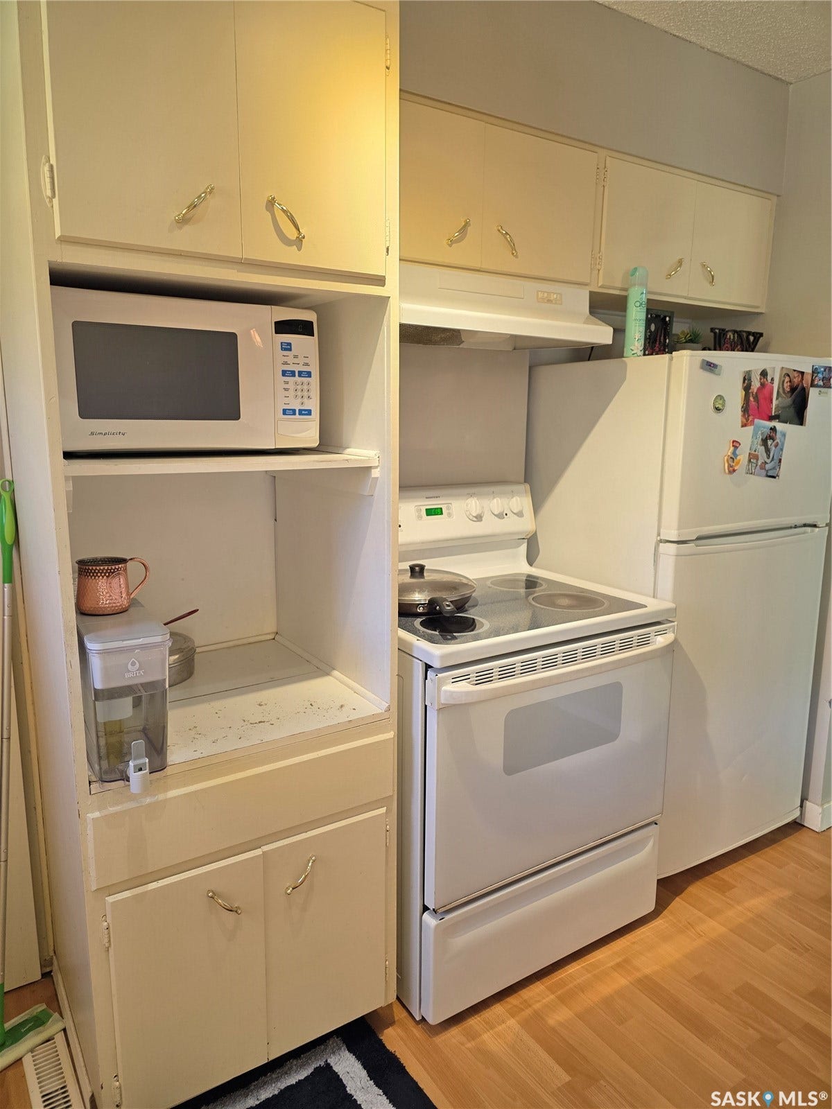 Built-in microwave cabinet, white overhead cabinetry, white electric range with exhaust hood, and light wood-finish flooring