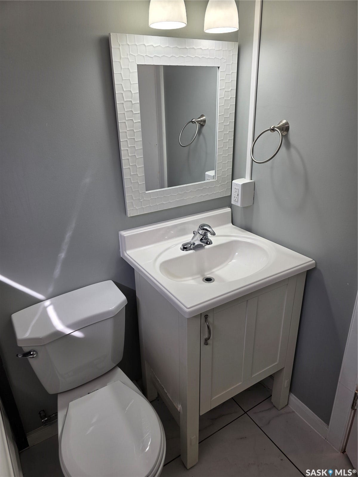 White vanity with an integrated sink, brushed nickel faucet, and a decorative framed mirror