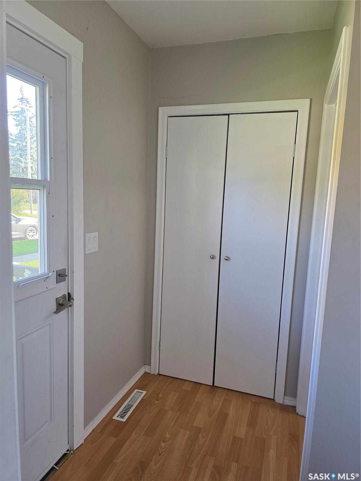 Entryway with wood-finish flooring, bi-fold closet doors, and light neutral wall paint