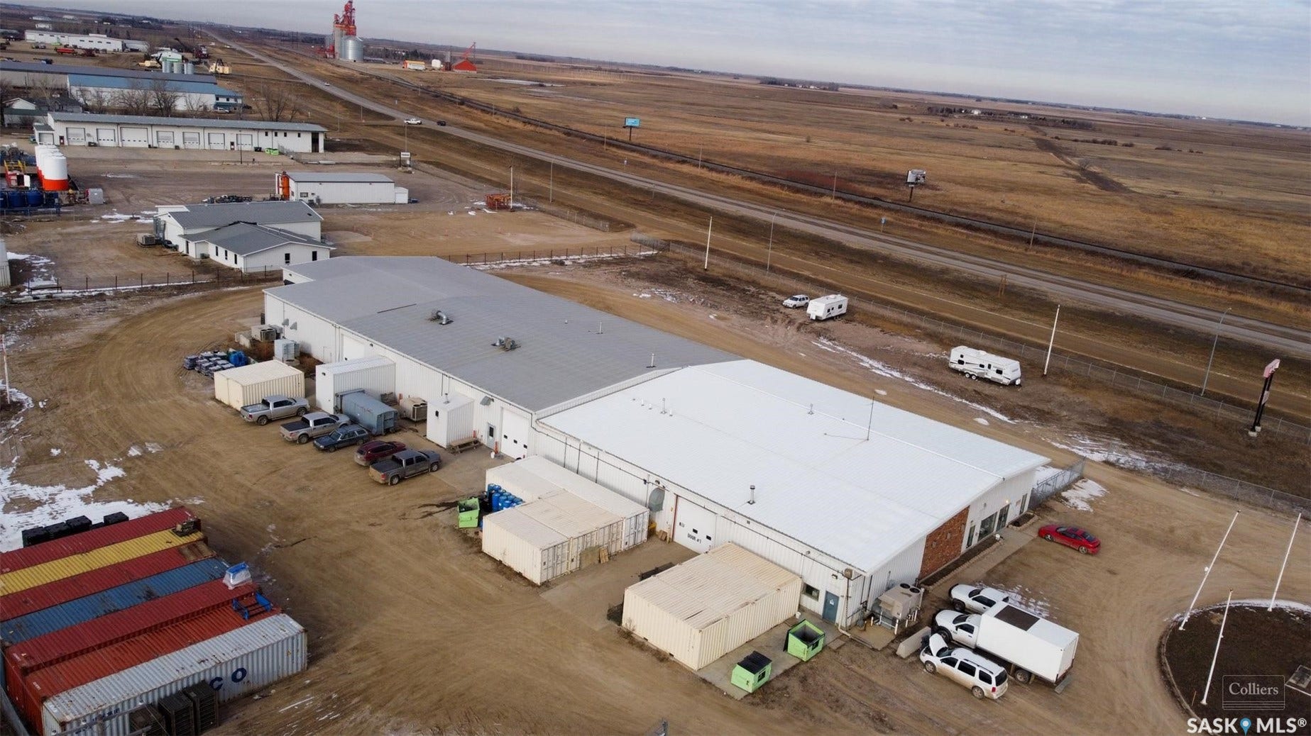 Industrial building with a flat roof, multiple garage doors, and an expansive unpaved lot