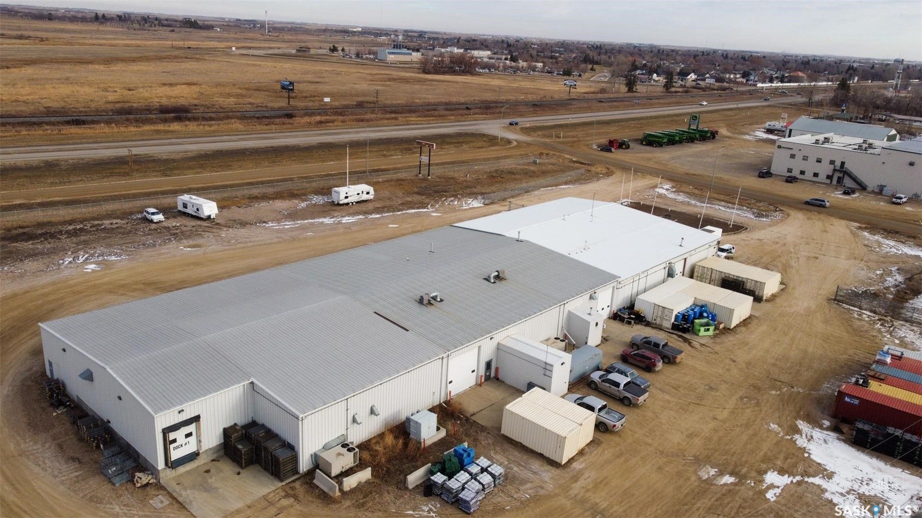 Expansive industrial building featuring multiple loading docks, a large paved lot, and a metal roof