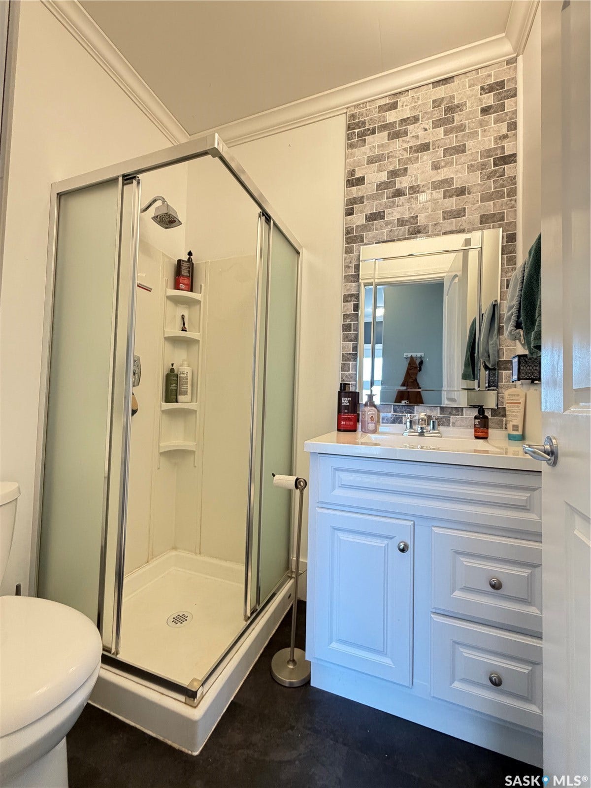 White vanity with a single basin sink, chrome faucet, and mirrored framed vanity mirror