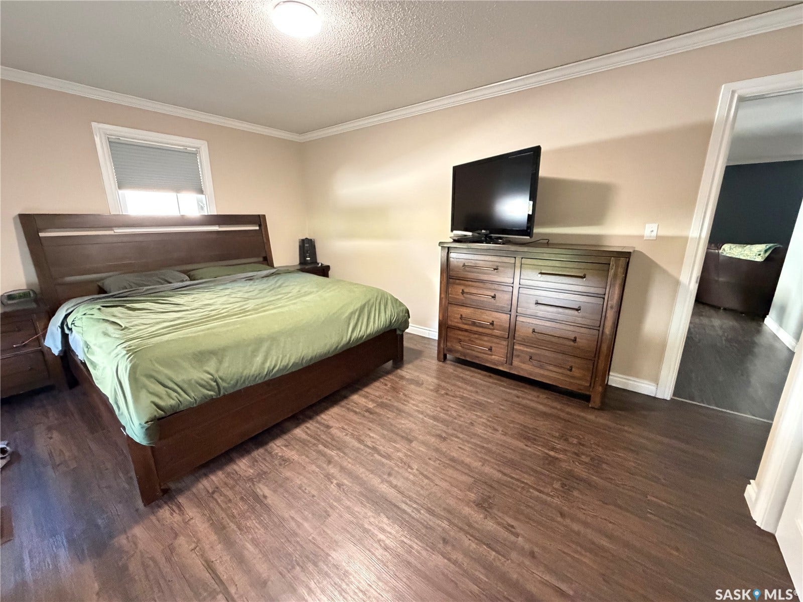 Wood-finish flooring throughout, light-toned wall paint, white crown molding, and a flush-mount ceiling light