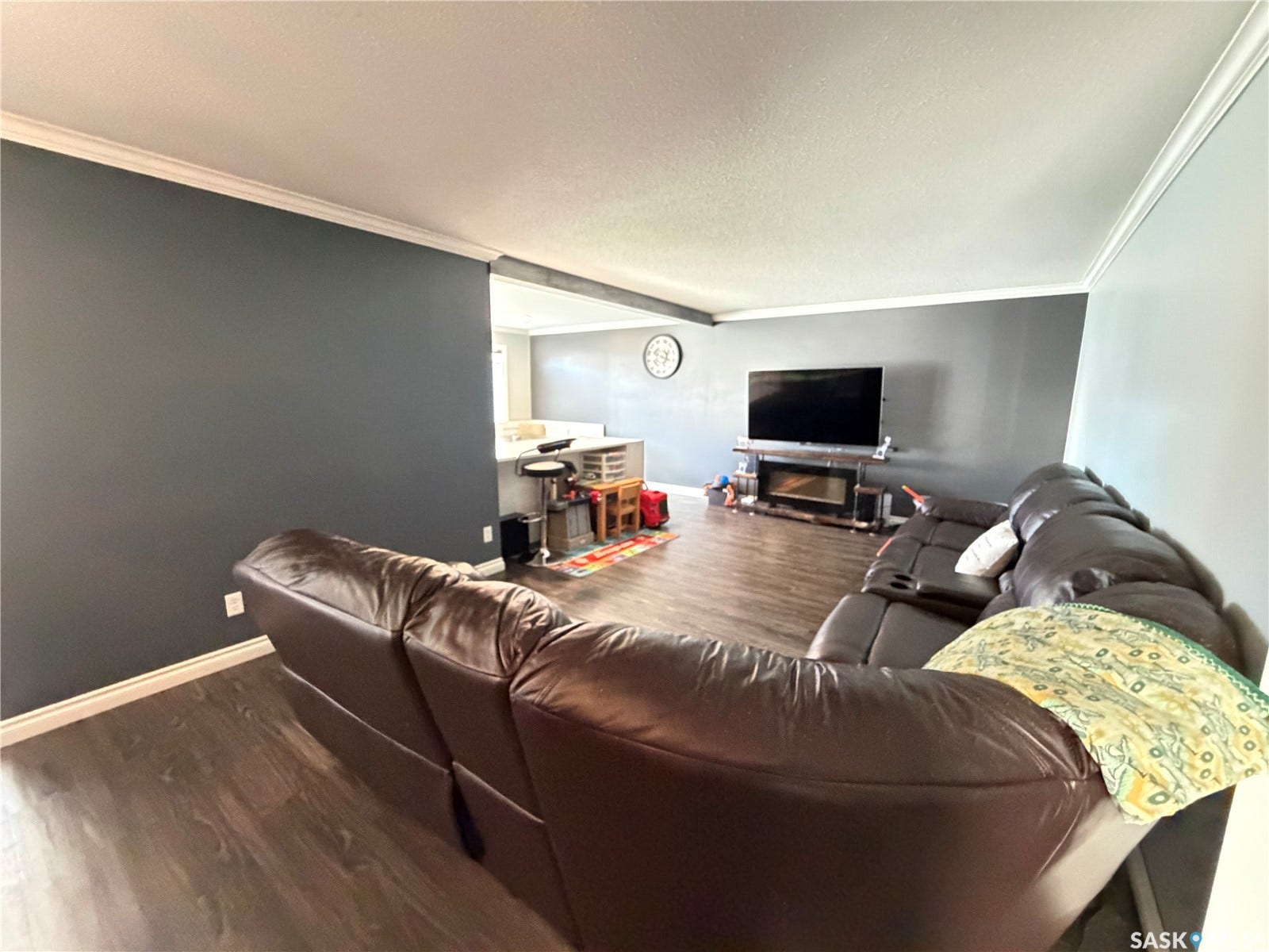 Wood-finish flooring throughout, featuring crown molding and a fireplace with a dark mantel