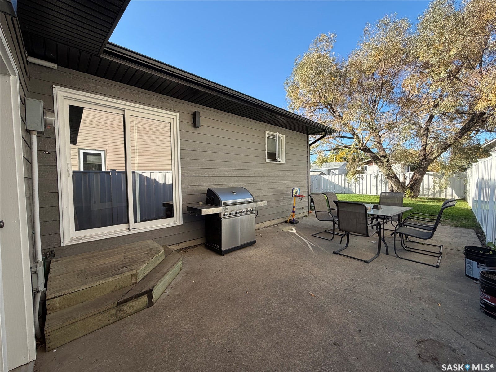Paved patio area, white privacy fencing, siding exterior, black soffit and fascia, sliding glass door