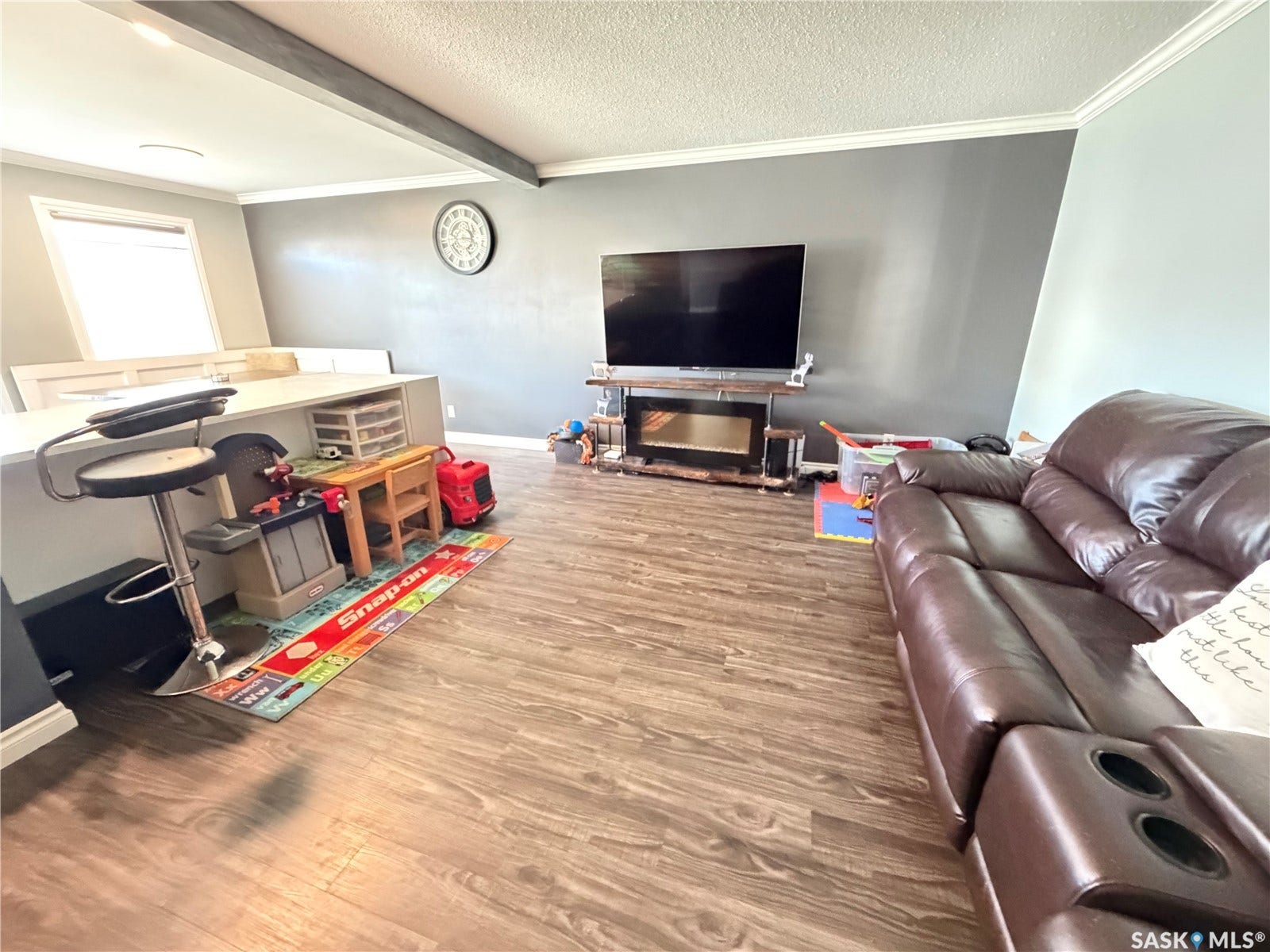 Wood-finish flooring with crown molding and a built-in kitchen island featuring a countertop