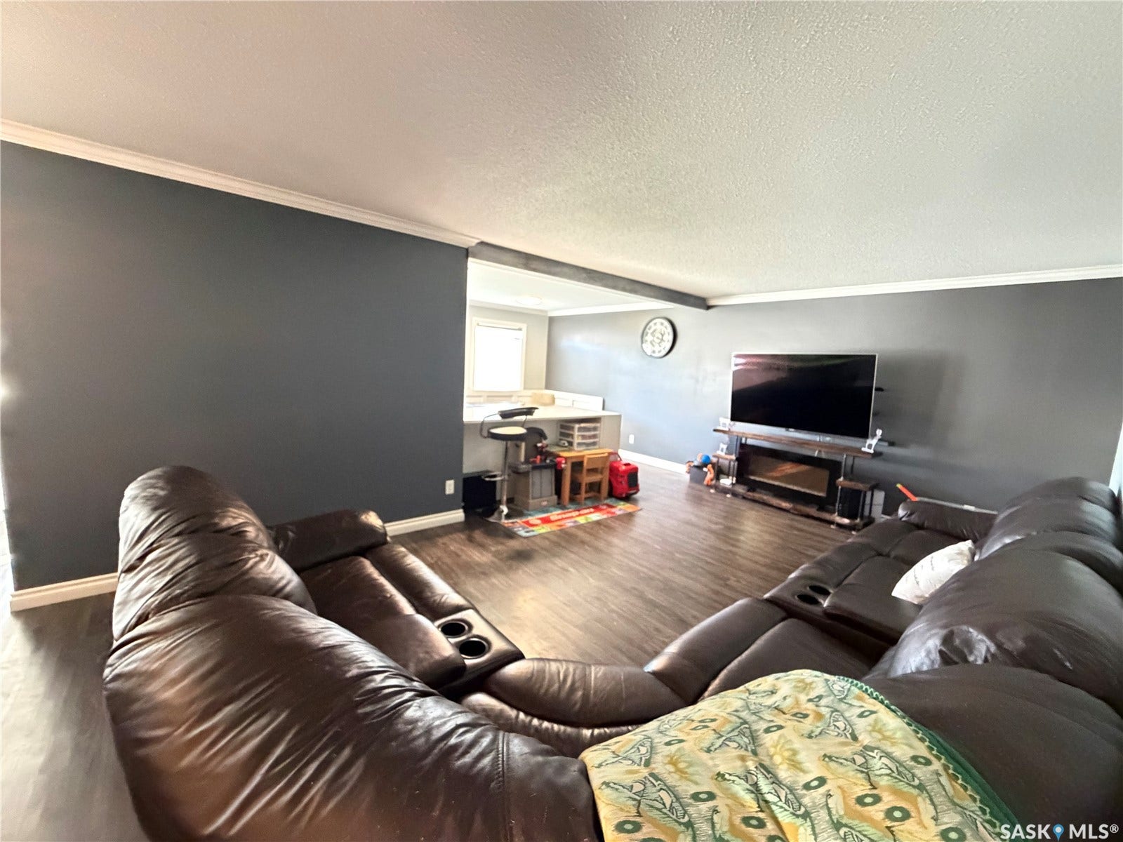 Wood-finish flooring throughout, crown molding, and an electric fireplace with an integrated media console