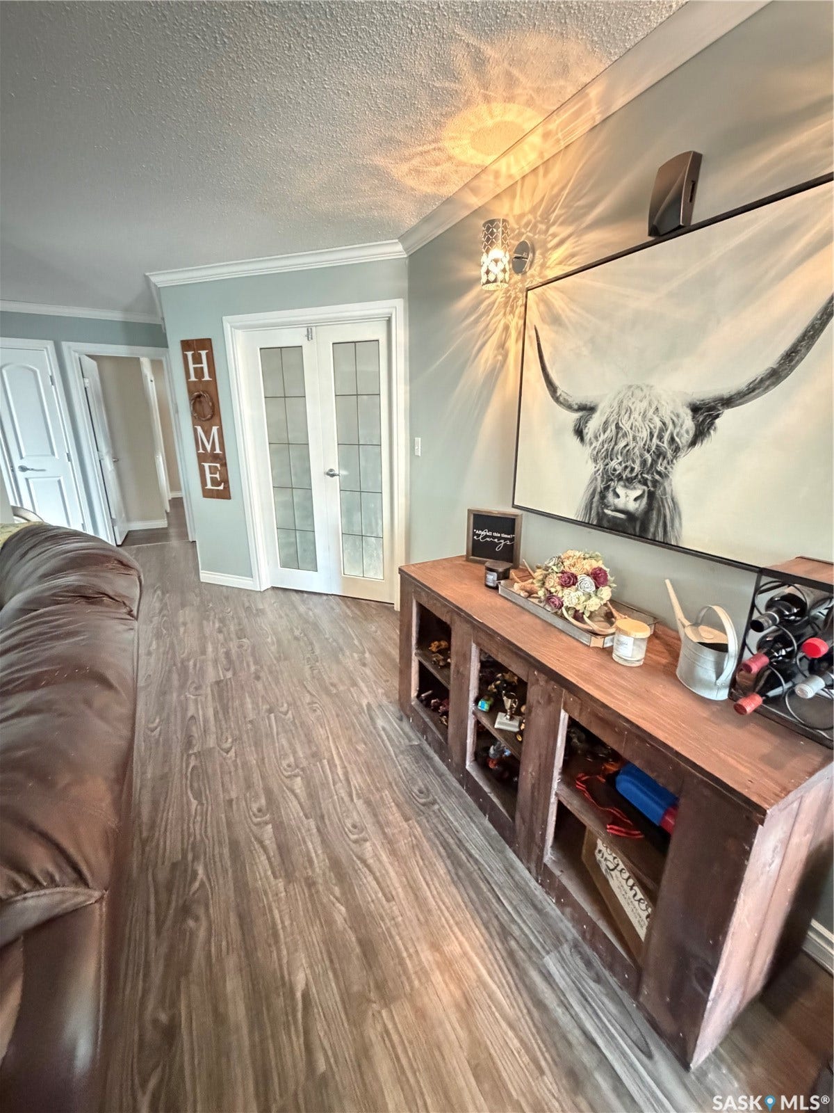Wood-finish flooring with crown molding and wall sconce