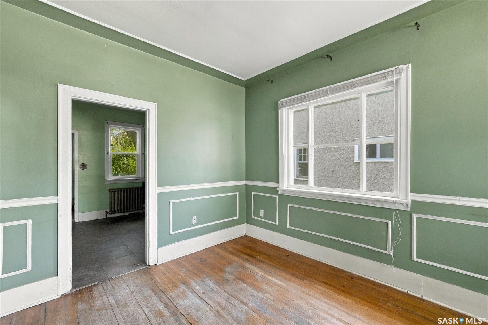 Paneled wall accents, wood flooring, and a multi-pane window
