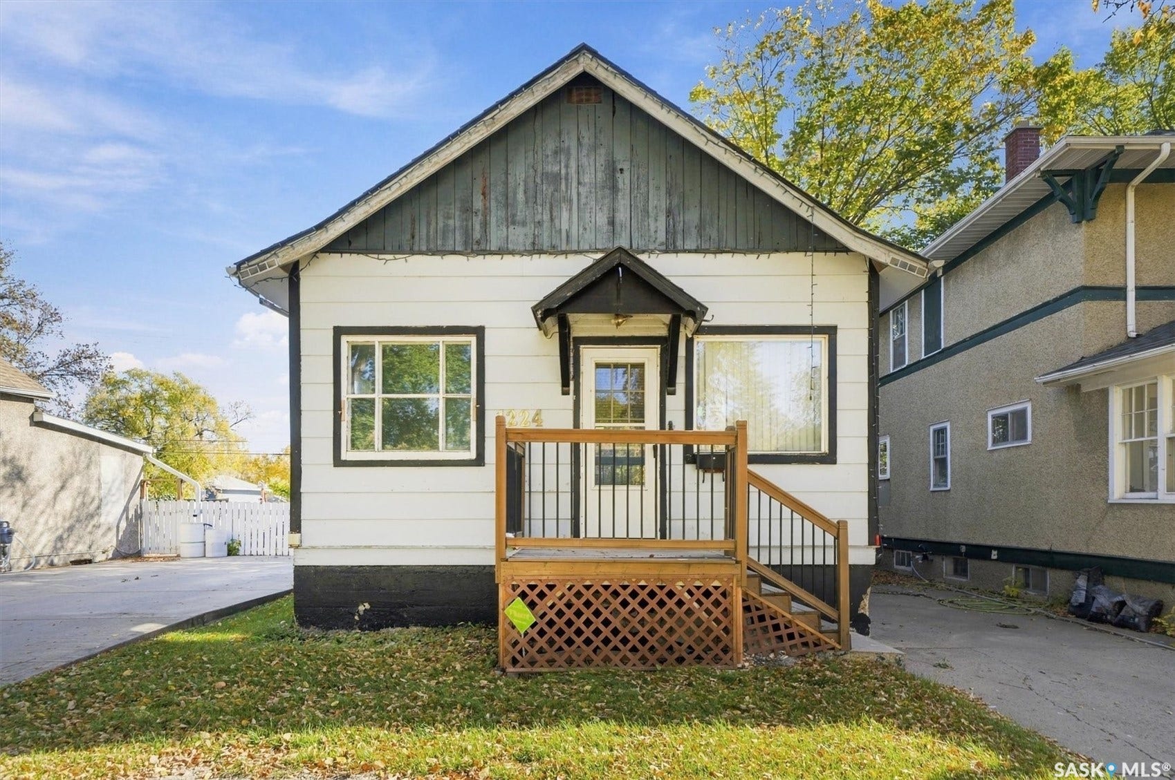 White exterior siding with dark trim, featuring a covered front entry with wooden porch and railings