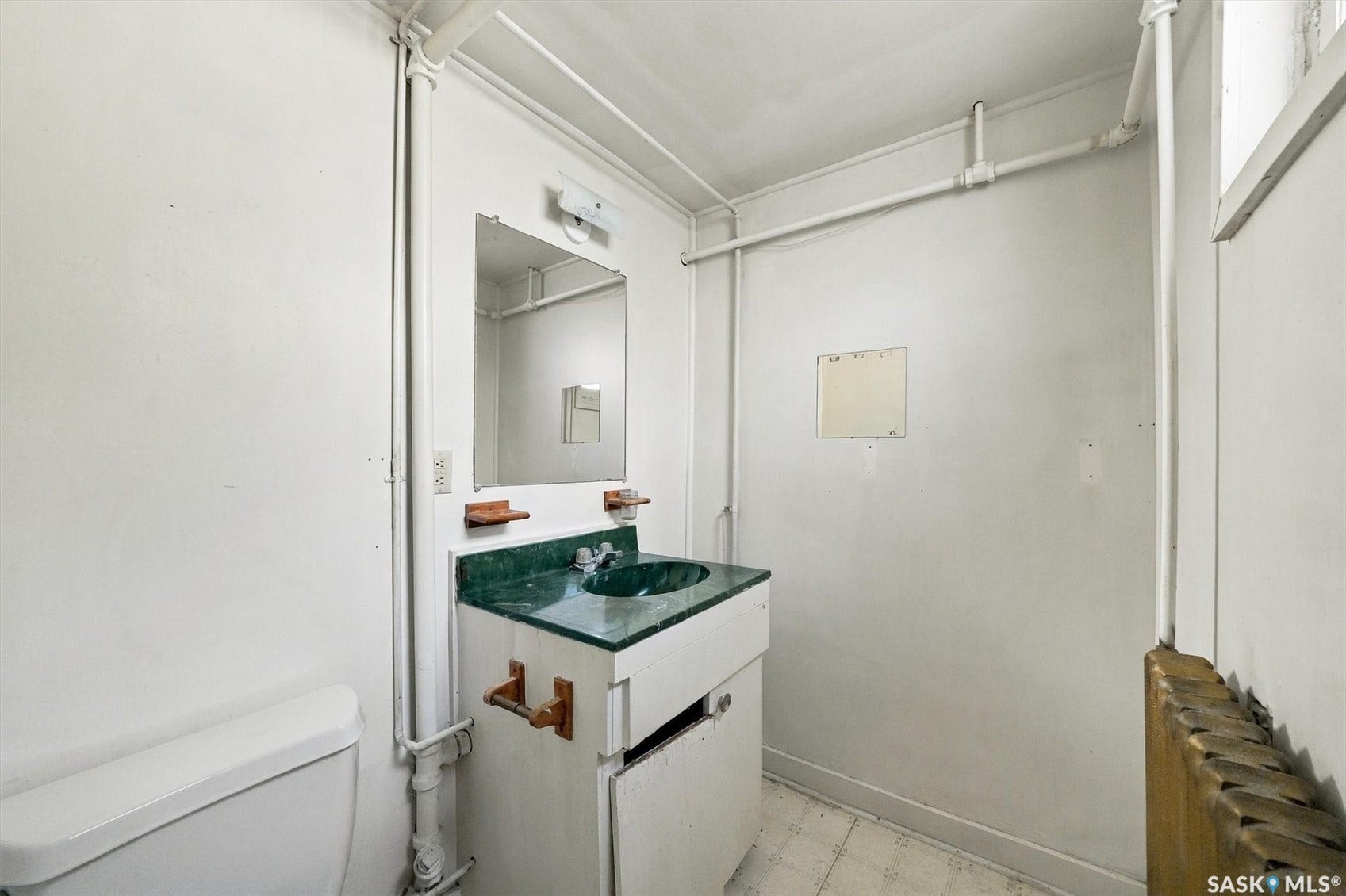 Vanity with green countertop and integrated sink, wall-mounted mirror, and white toilet