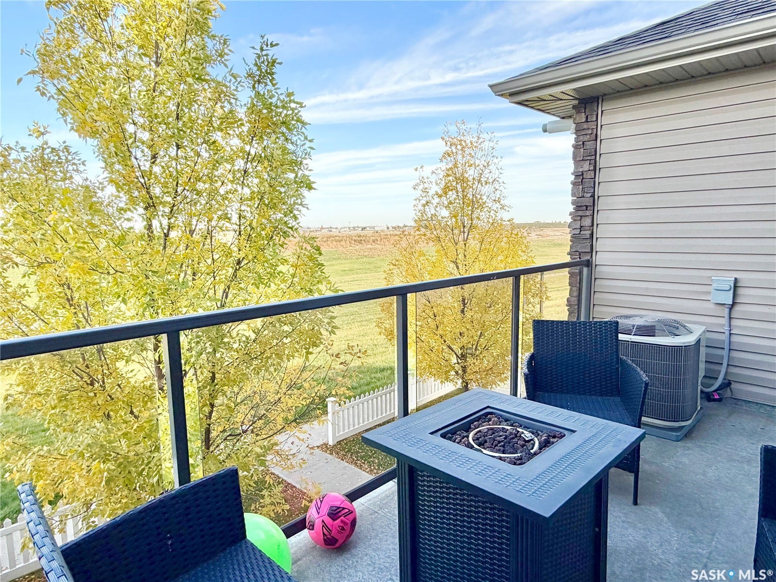 Balcony with glass railing, concrete flooring, and an exterior wall featuring horizontal siding and stacked stone accents