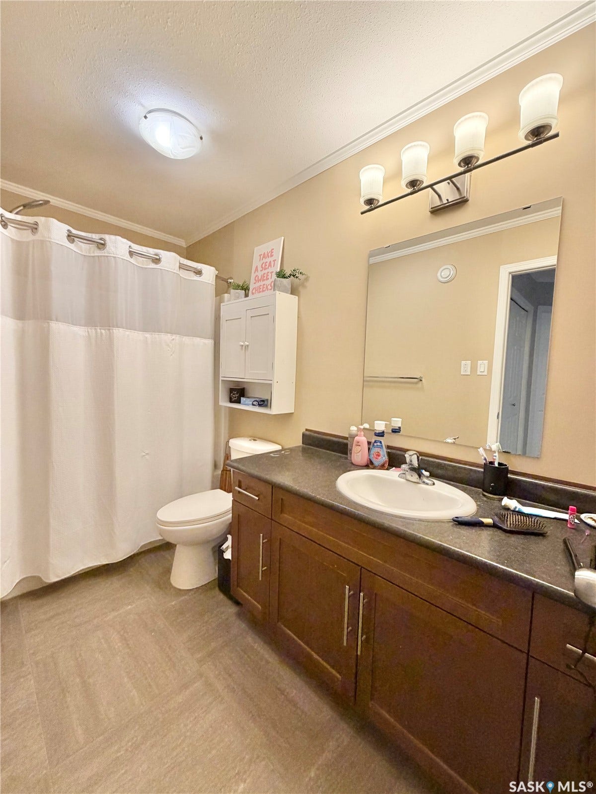 Vanity with a single basin, dark wood-finish cabinetry, and a full-width mirror