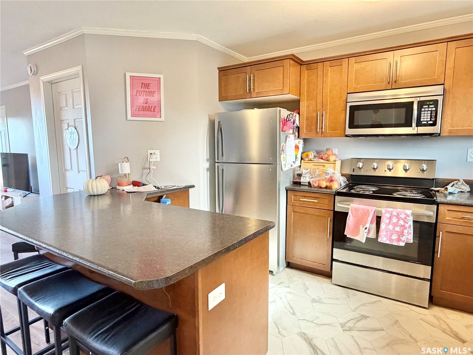 Kitchen featuring a peninsula with seating, stainless steel appliances, wood-finish cabinetry, and patterned tile flooring