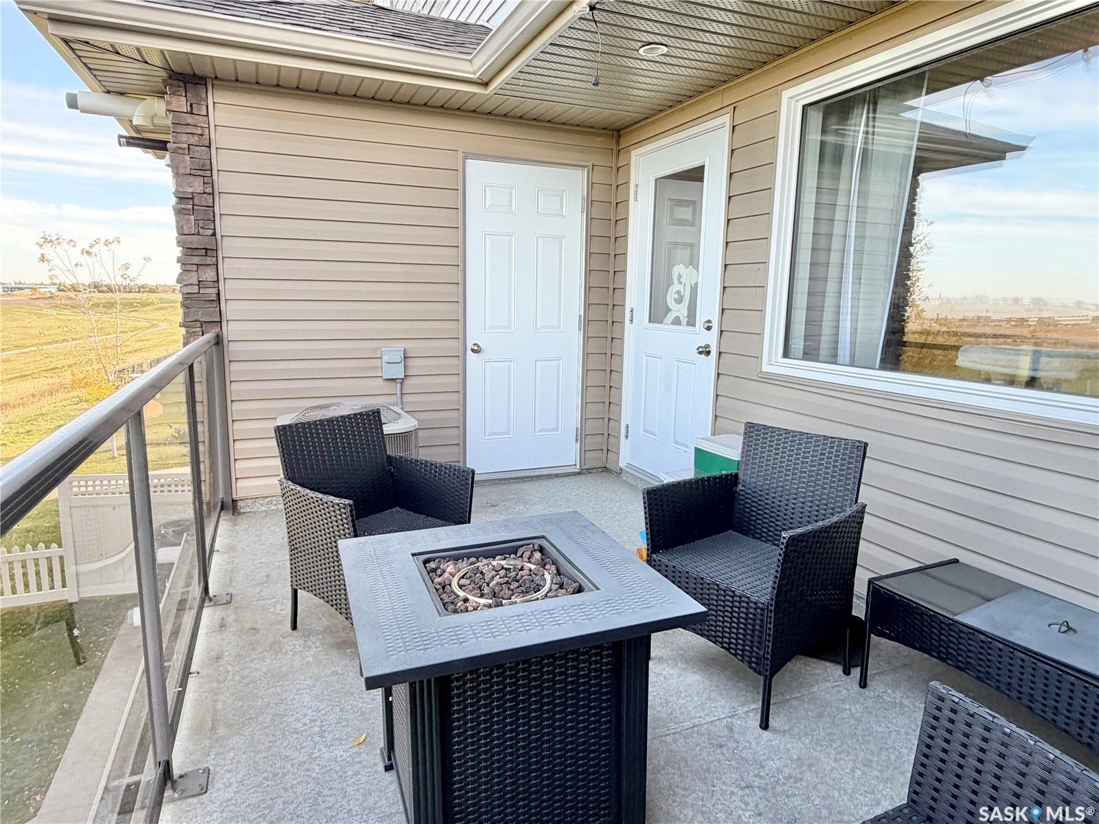 Concrete patio featuring glass panel railing, stone veneer accent, and horizontal siding
