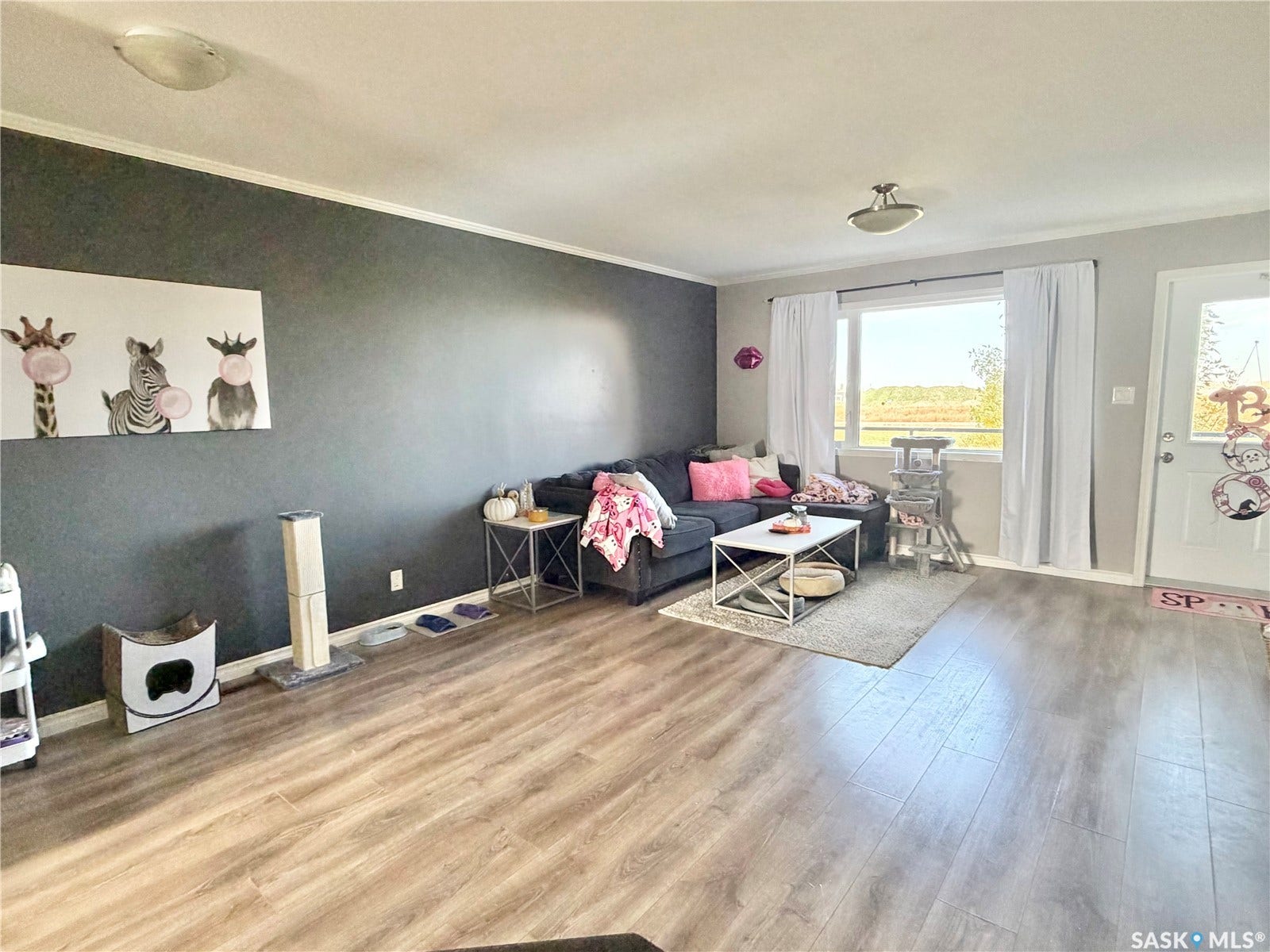 Wood-finish flooring throughout, featuring a large window, and crown molding