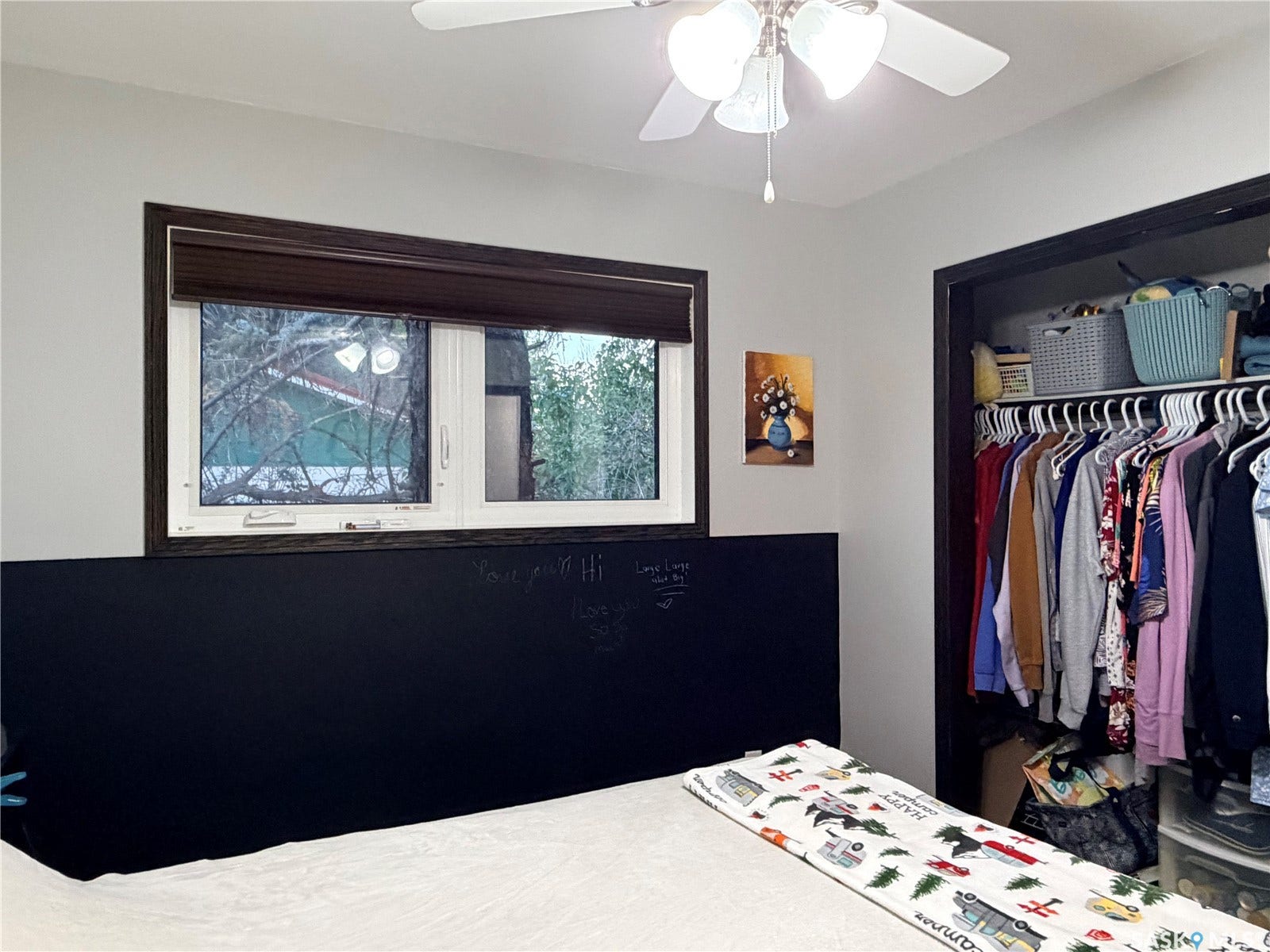 Window with dark wood trim, ceiling fan with integrated lighting, and a built-in closet with shelving